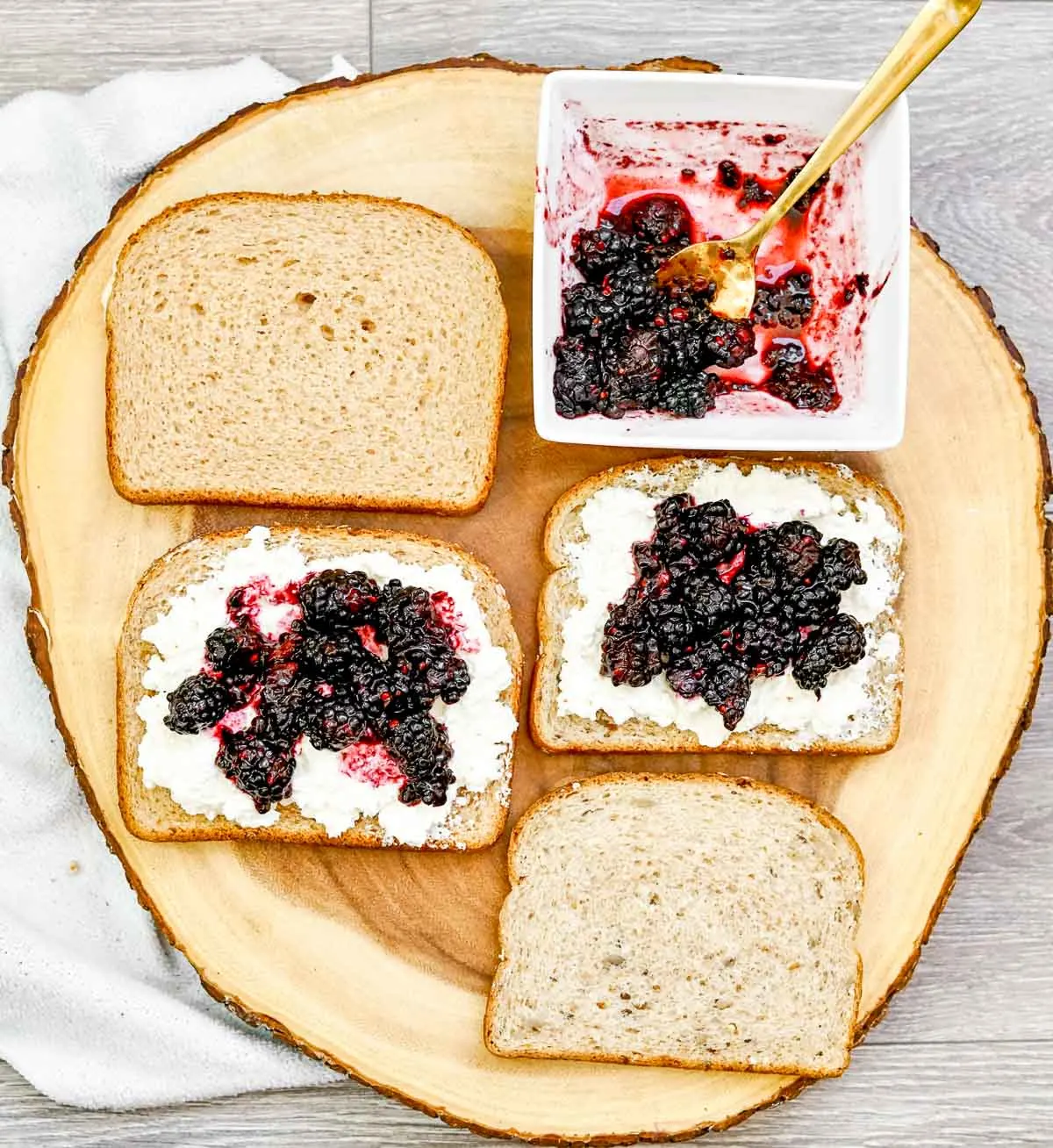 Spreading mashed blackberries over goat cheese on bread.