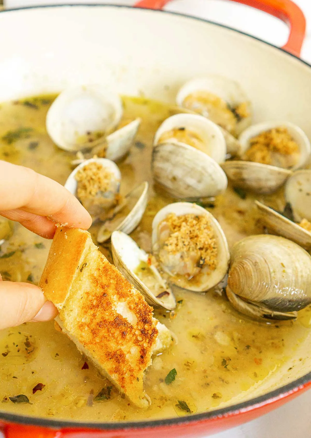 Dipping bread into white wine sauce for clams