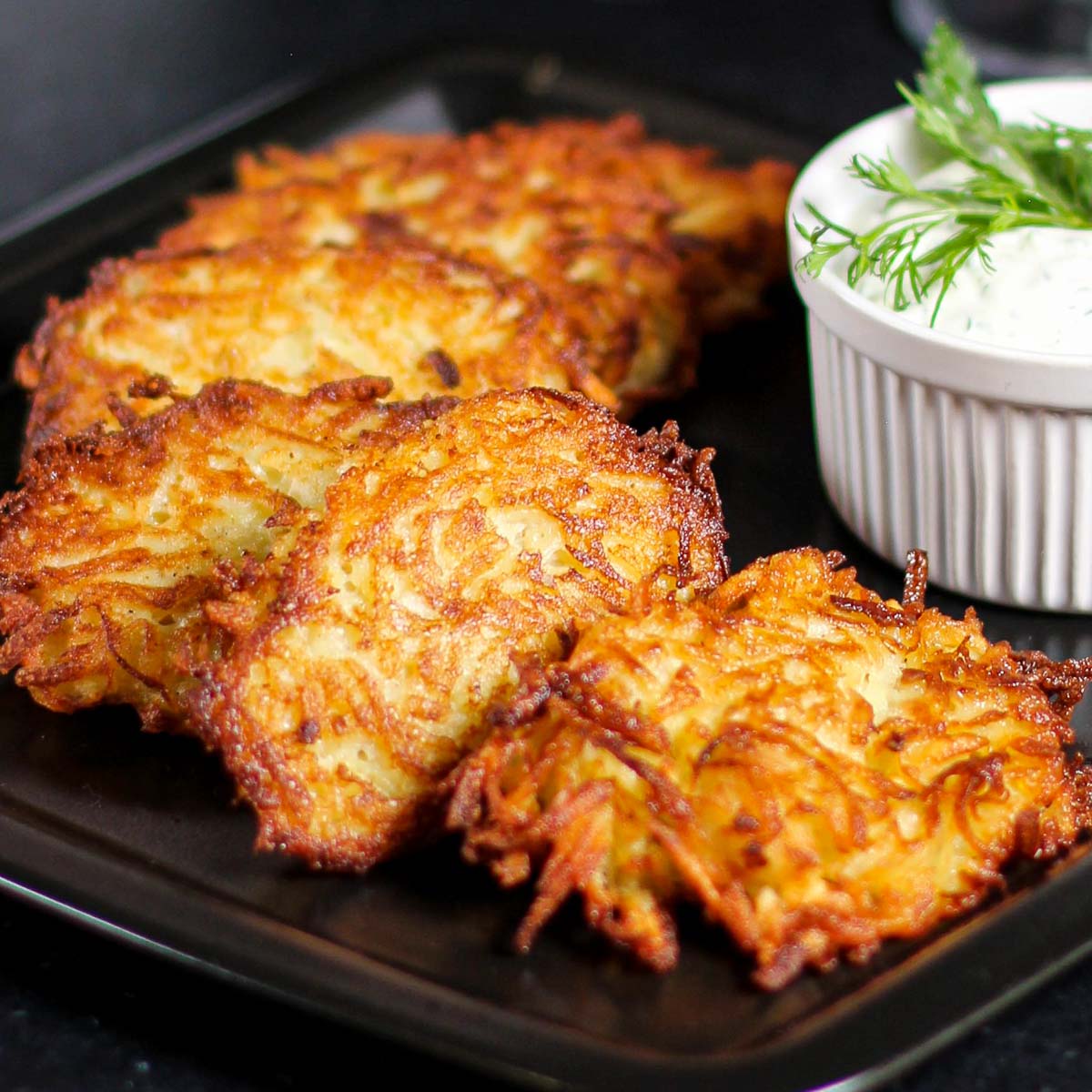 Russian potato fritters on a plate with a cup of sour cream