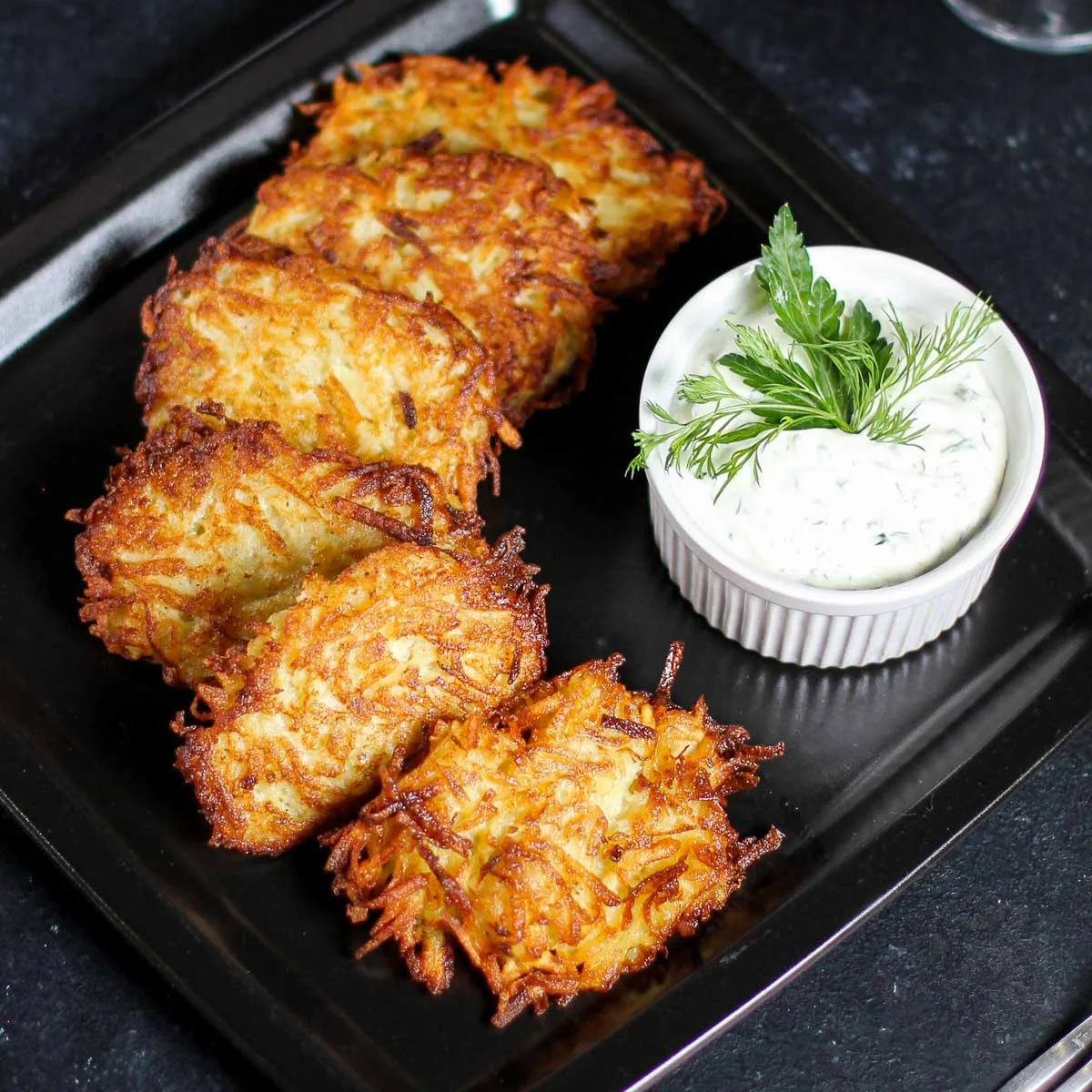 Plate of latkes with a bowl of sour cream