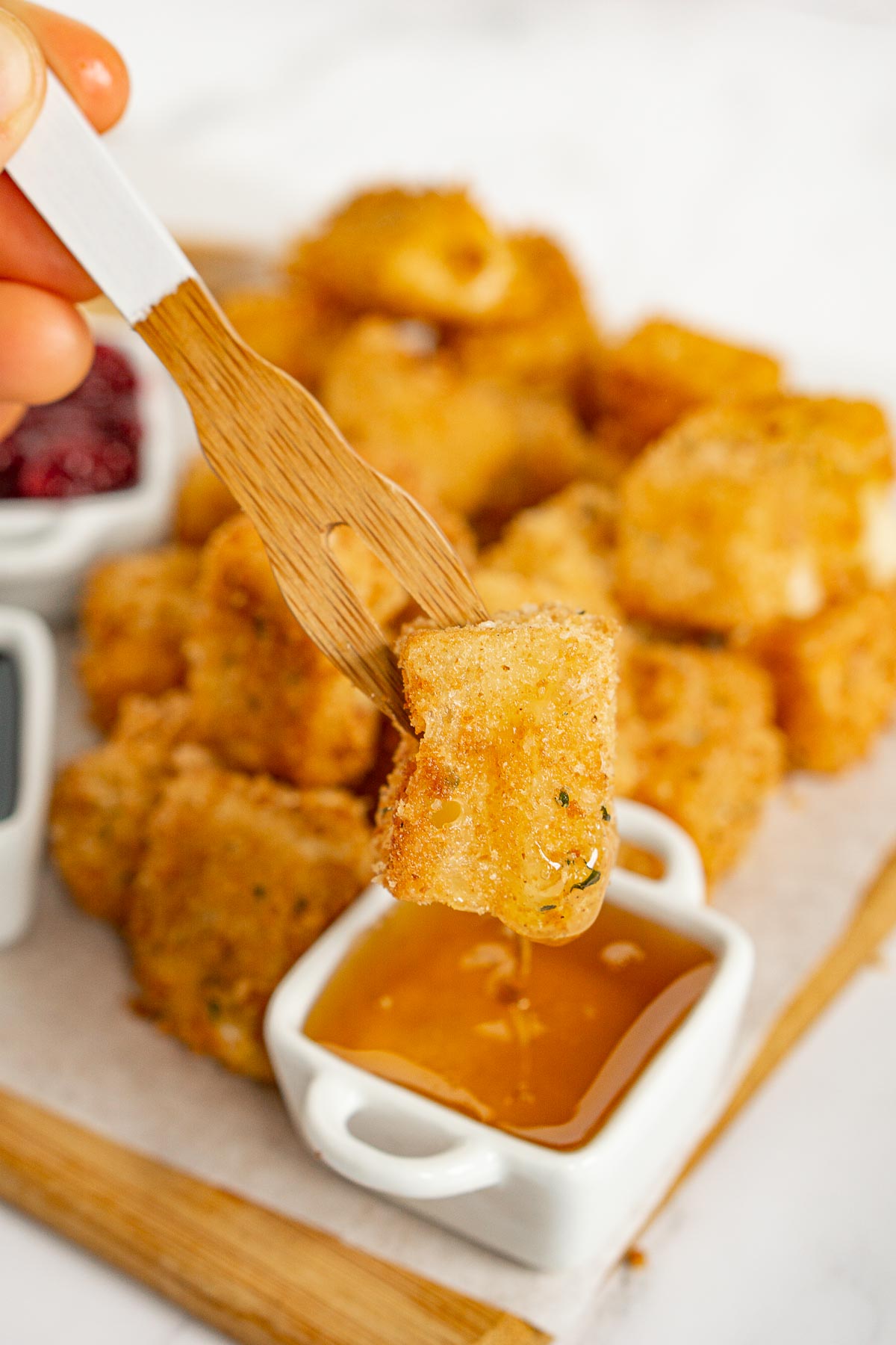 Dipping fried brie bite into honey