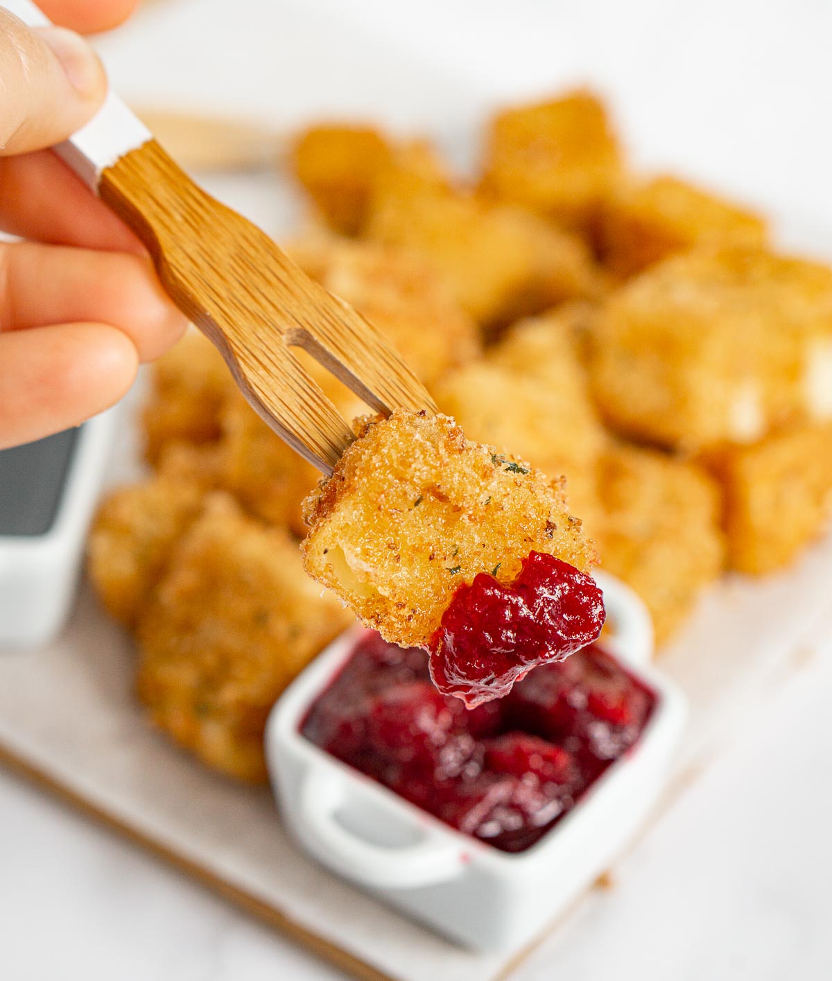 Dipping fried brie appetizer into cranberry sauce