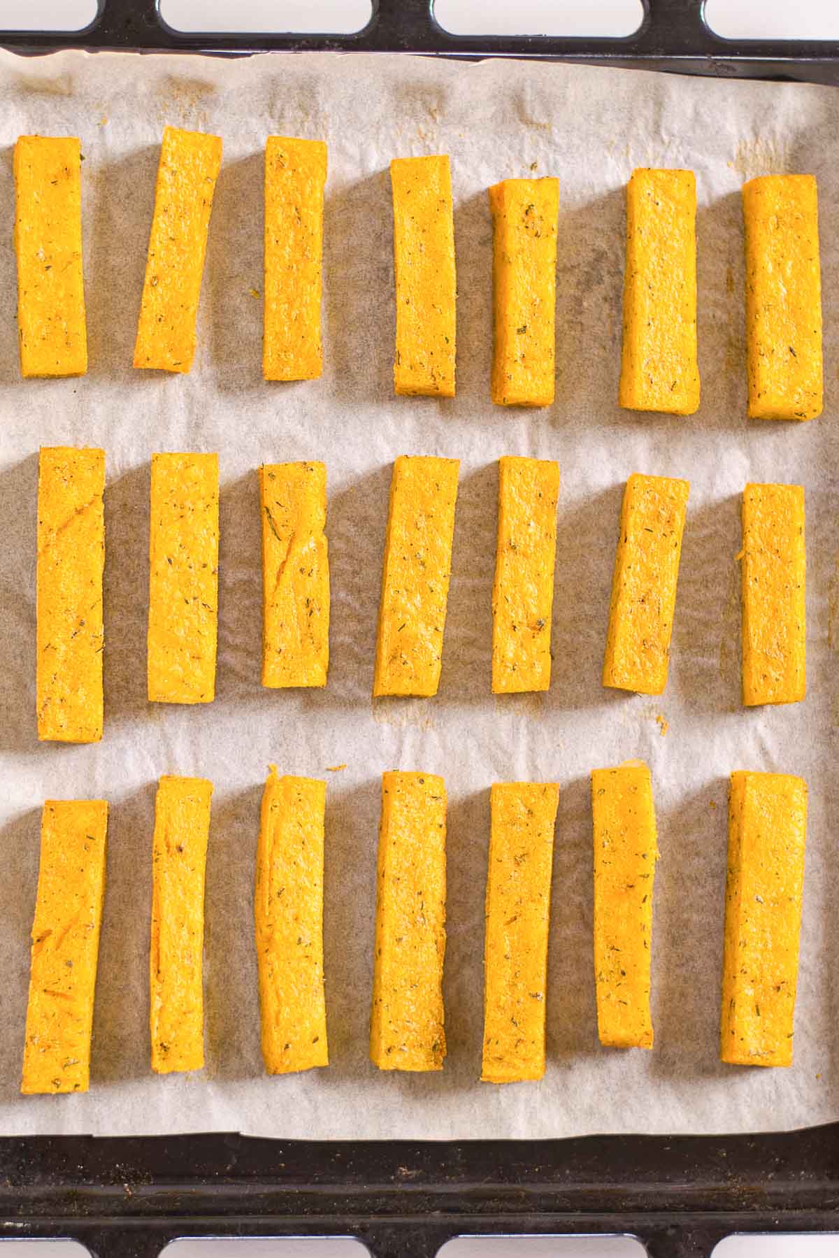 Polenta fries on a baking sheet with parchment paper.