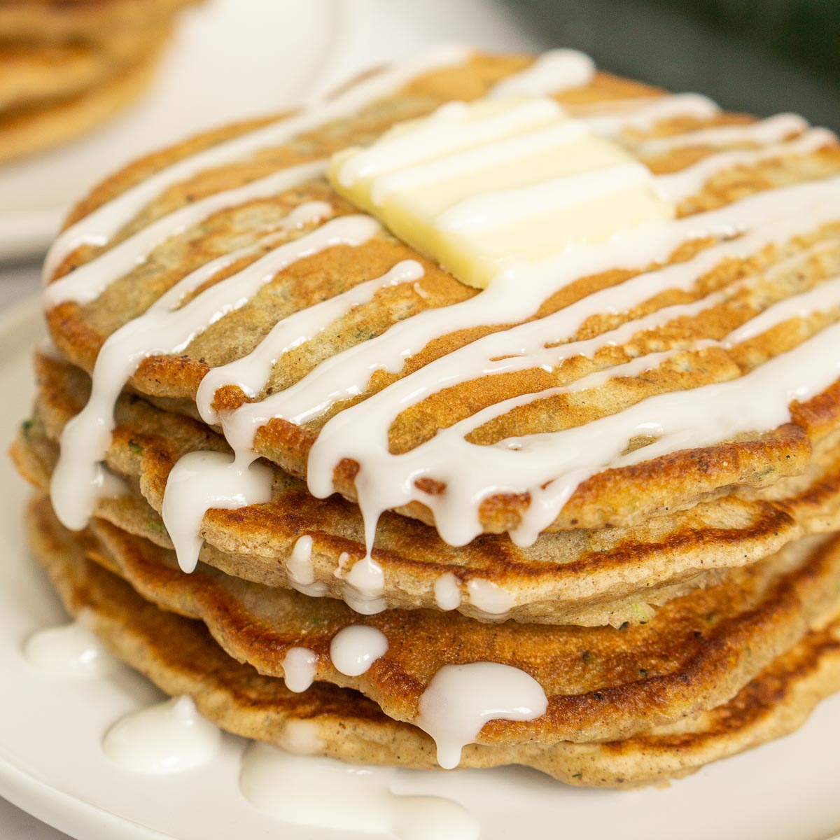Stack of zucchini bread pancakes with lemon glaze on top