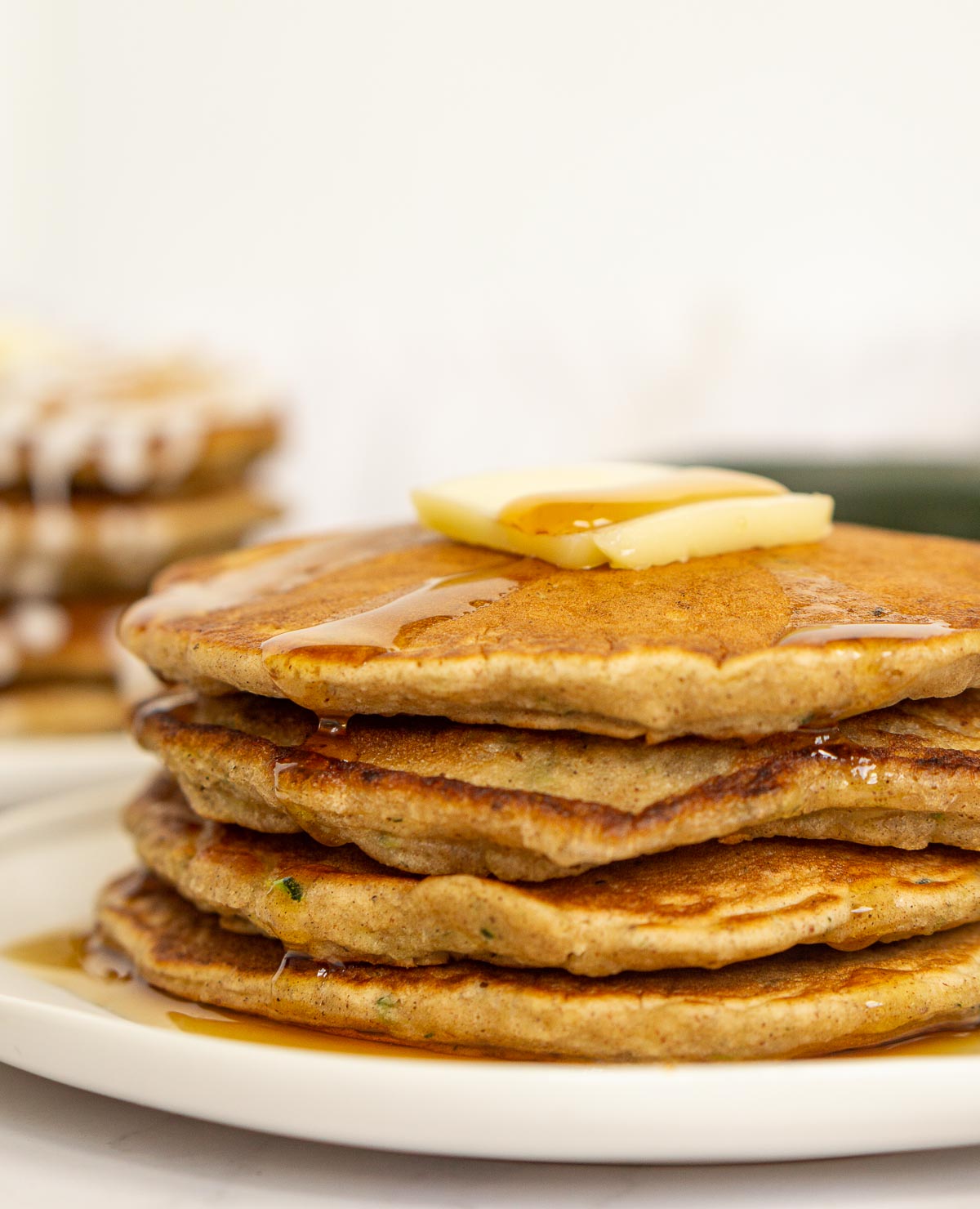 Stack of pancakes with zucchini, topped with maple syrup