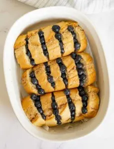 Hasselbacked baguette stuffed with blueberries ready to bake in a baking pan