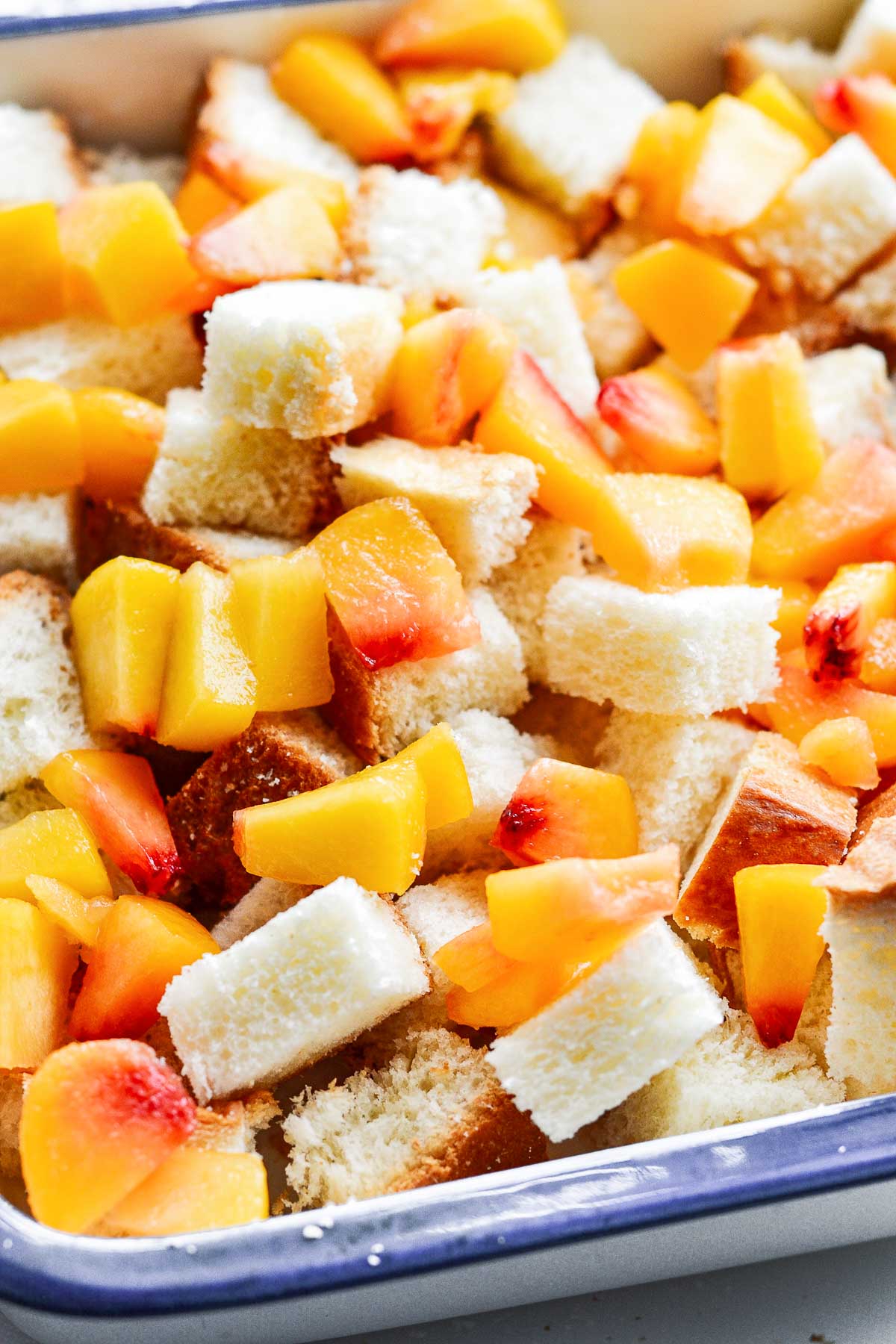 Diced peaches and cubed bread in a baking pan