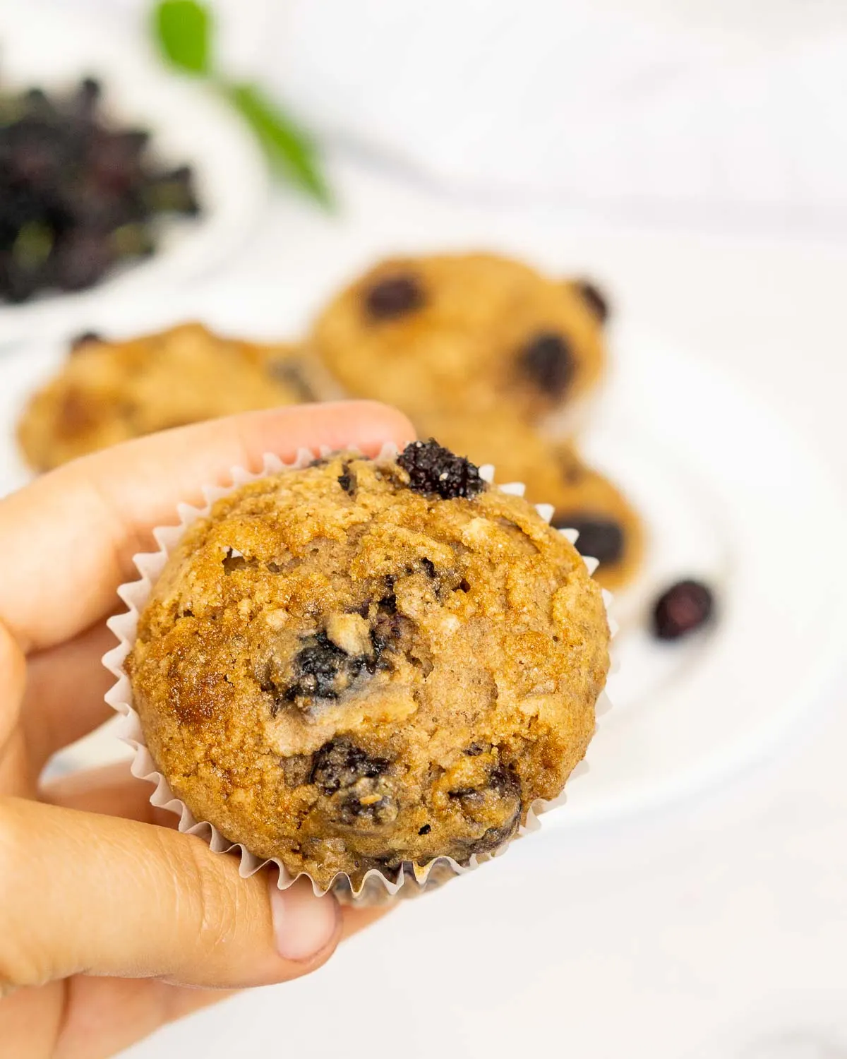 Hand holding mulberry muffin with brown sugar topping