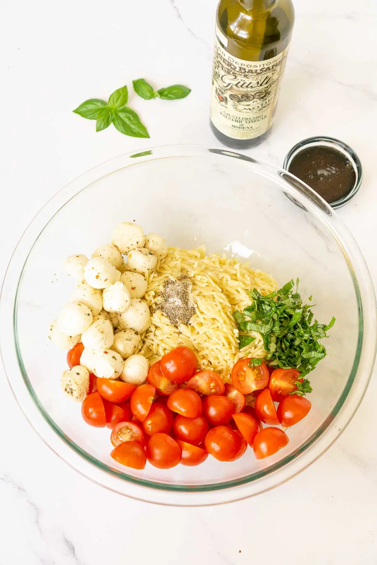 Orzo caprese salad ingredients in a mixing bowl