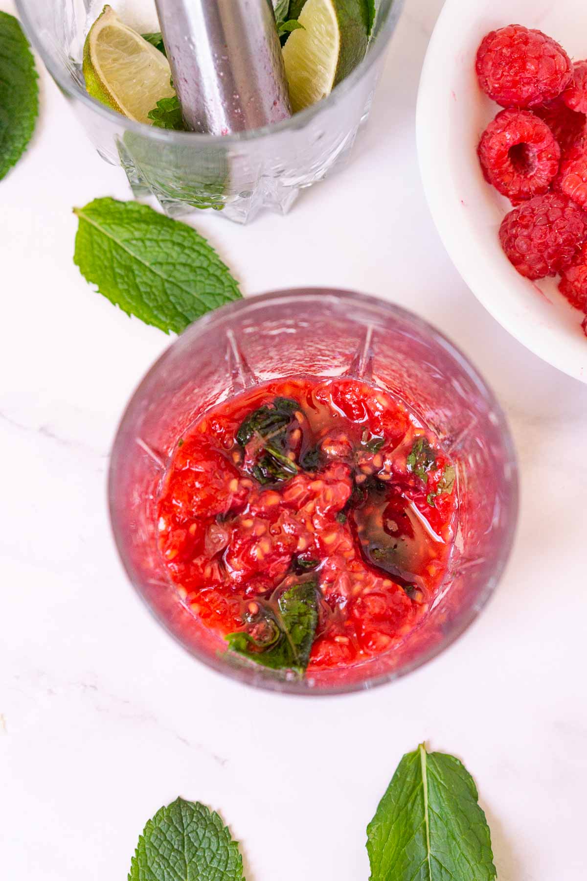 Muddled raspberries and mint in a glass