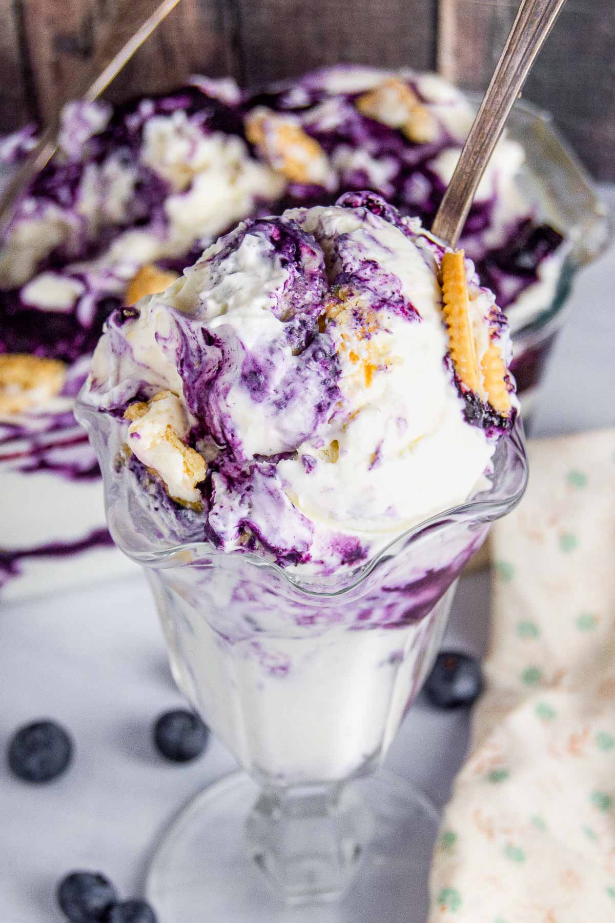 Close up of a scoop of blueberry cheesecake ice cream with cookies on top