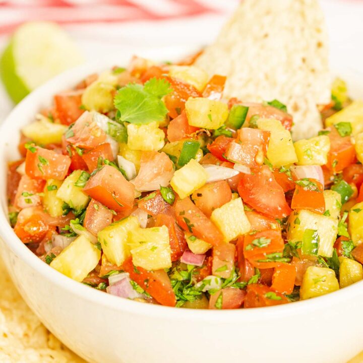 Bowl of pineapple pico de gallo with a tortilla chip on top