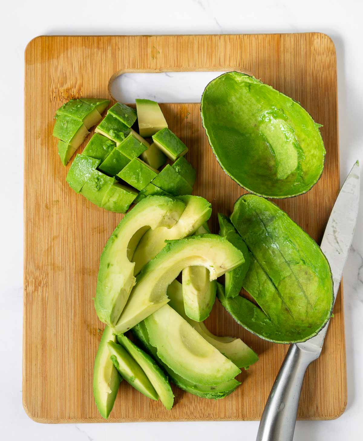 Cutting board showing avocado cut in 2 ways for Avocado Tempura