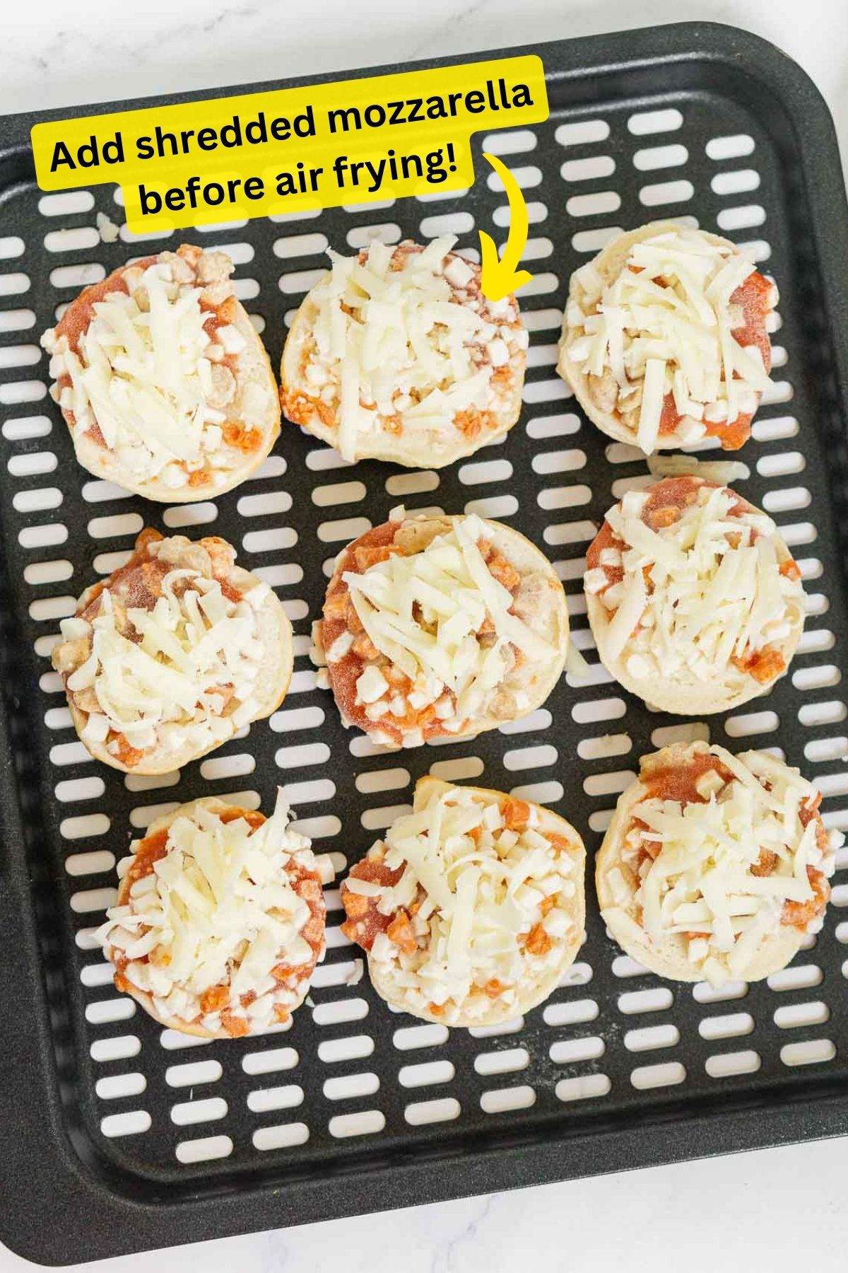 Bagel Bites on air fryer tray topped with shredded mozzarella