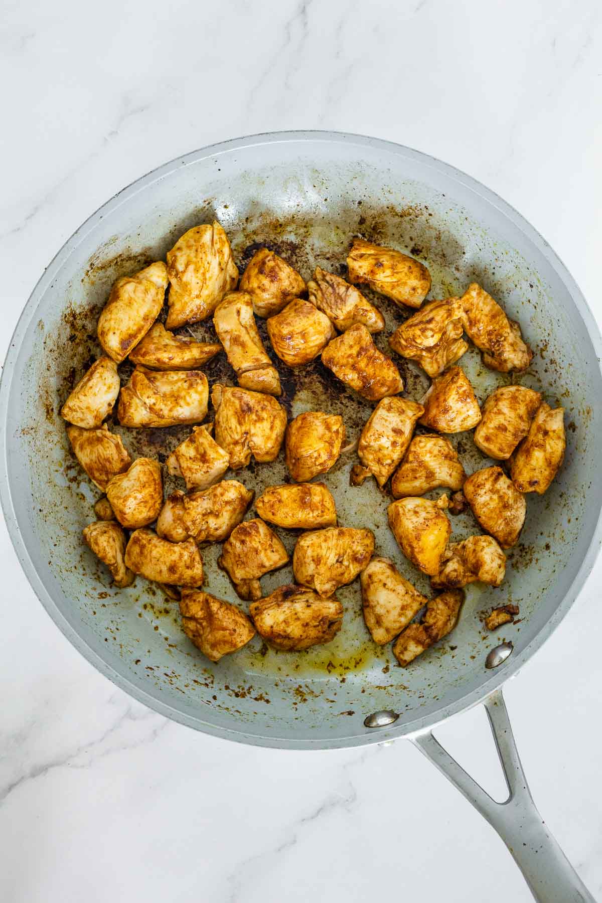 Browning blackened chicken bites in a pan