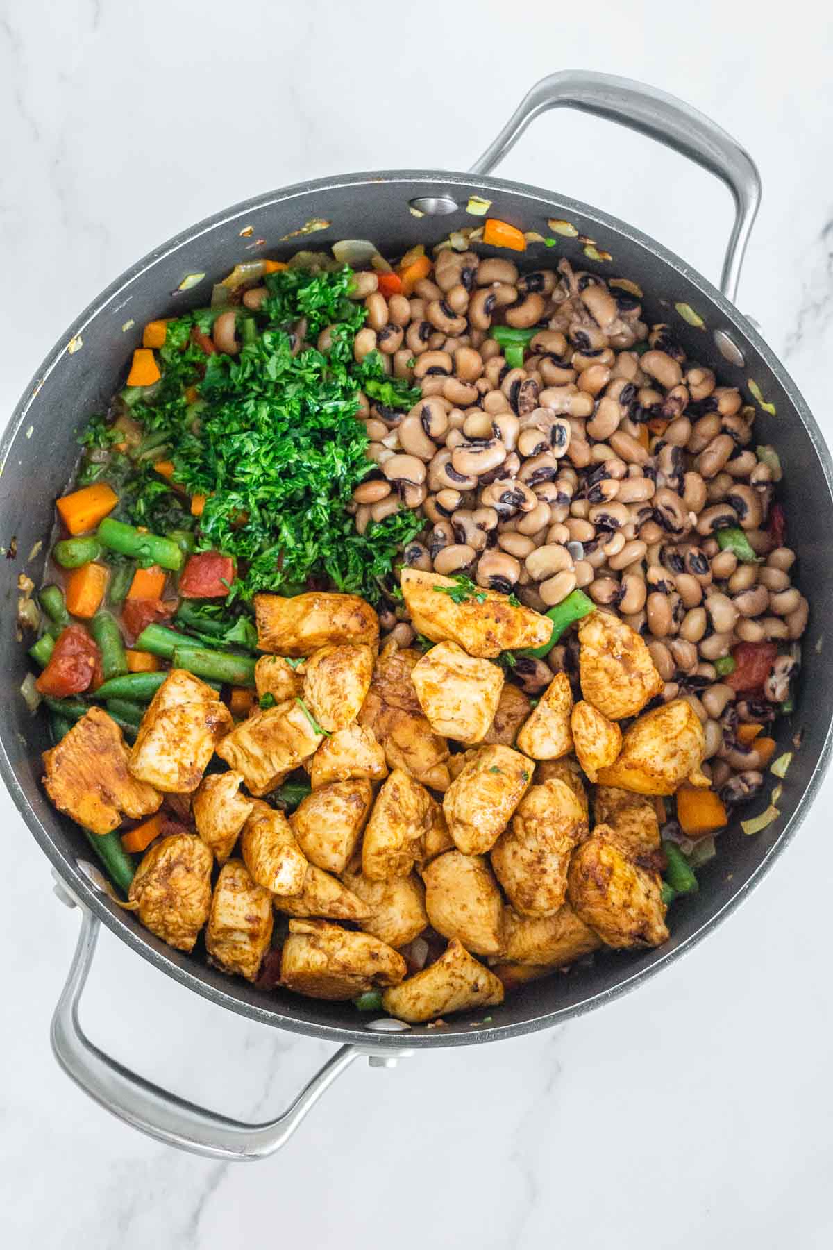 Black eyed peas, blackened chicken bites, and fresh herbs added to a pot