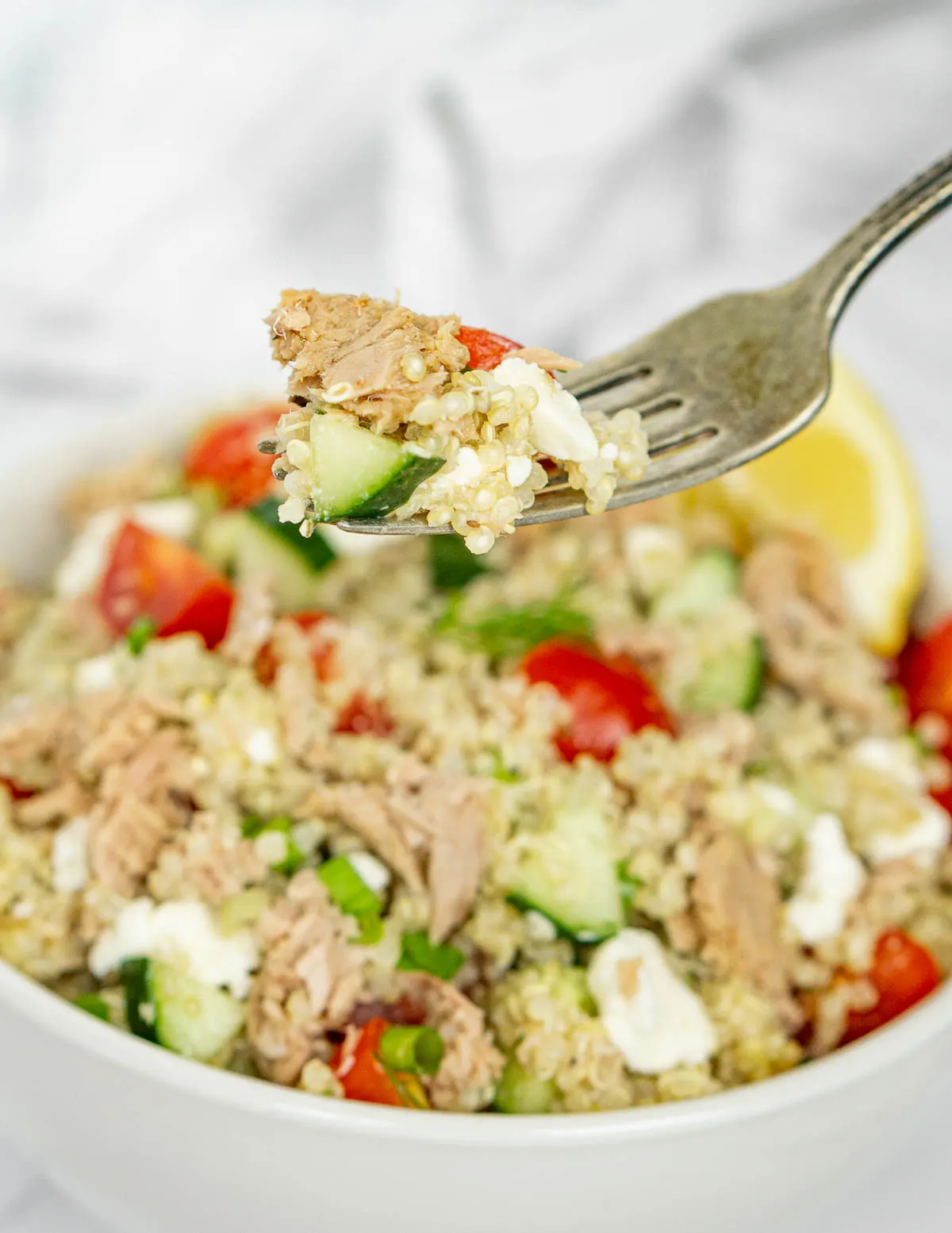 Fork holding tuna quinoa salad to show texture.