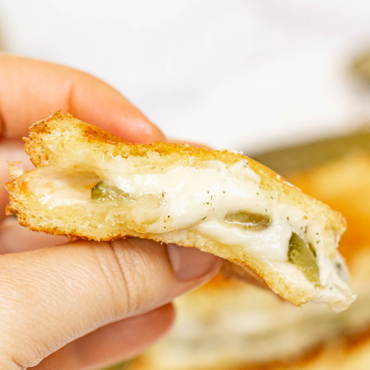 Hand holding melty pickle grilled cheese
