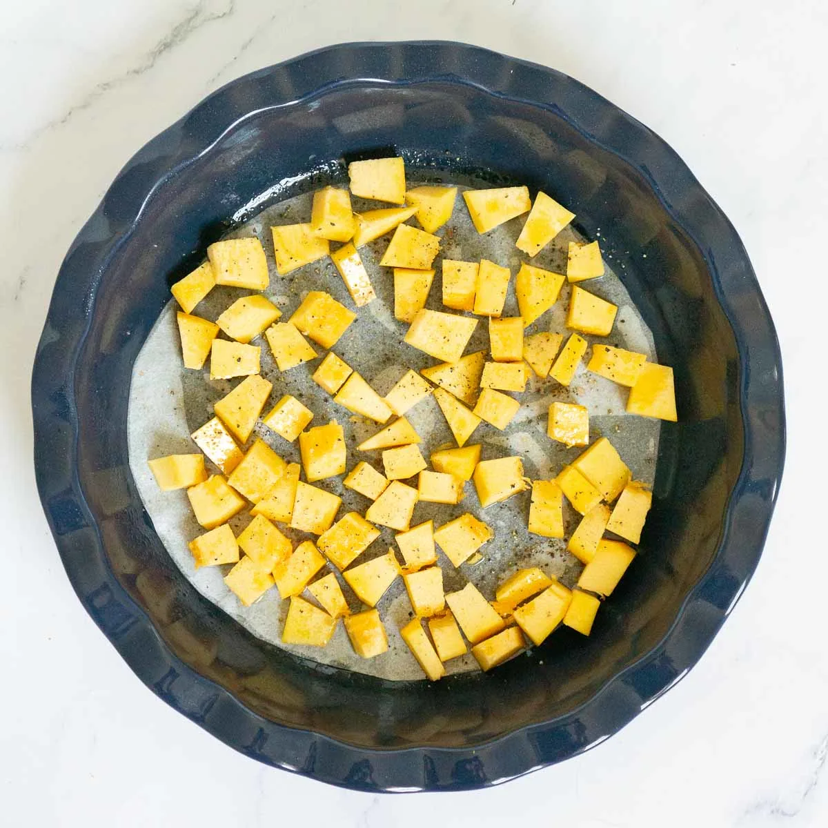Cubed pumpkin in a pie dish ready to be roasted