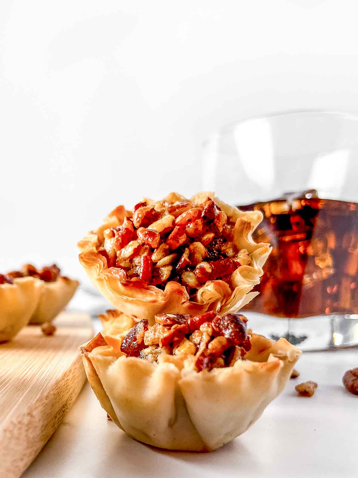 2 pecan pie phyllo cups with glass of bourbon in the background