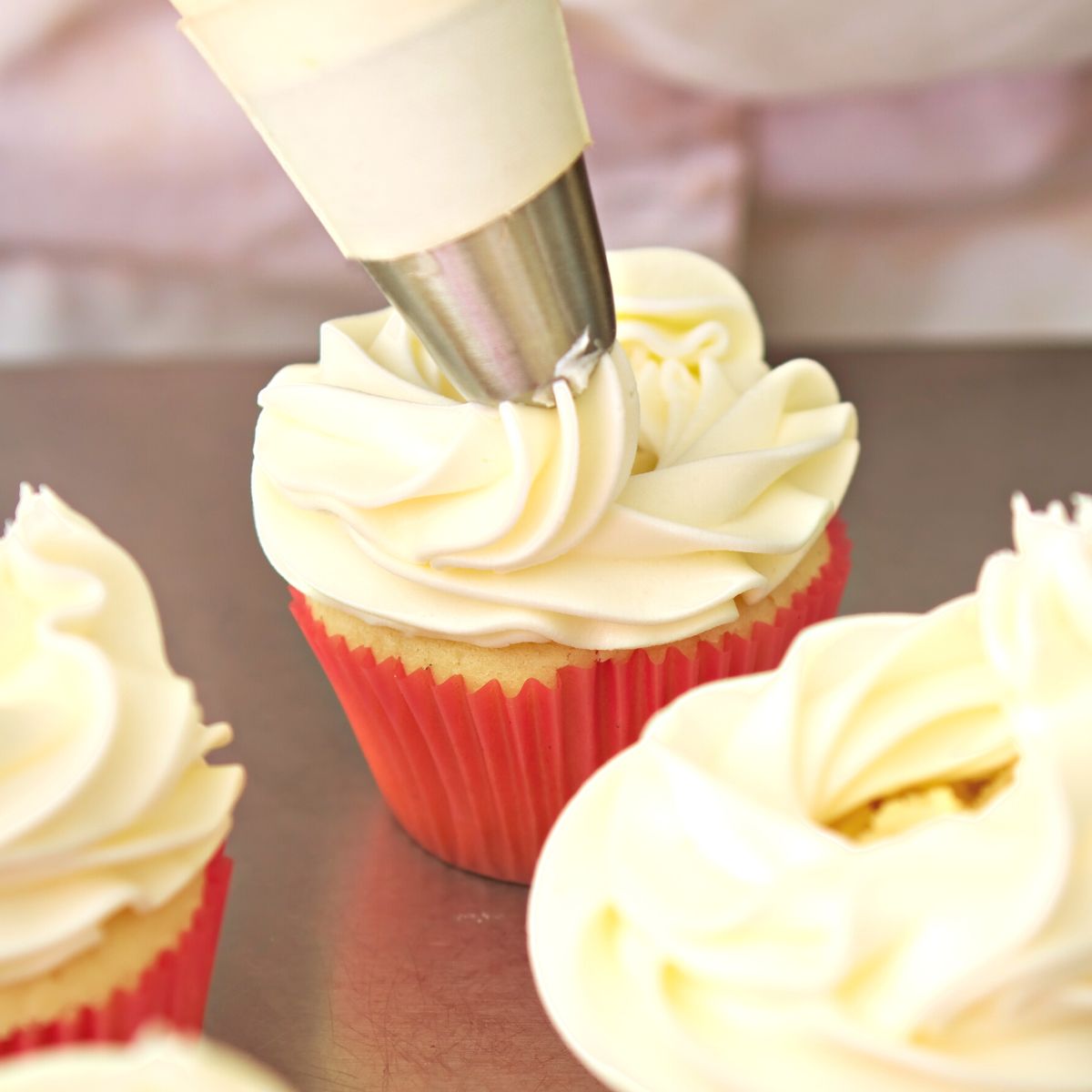 Piping champagne frosting onto cupcakes