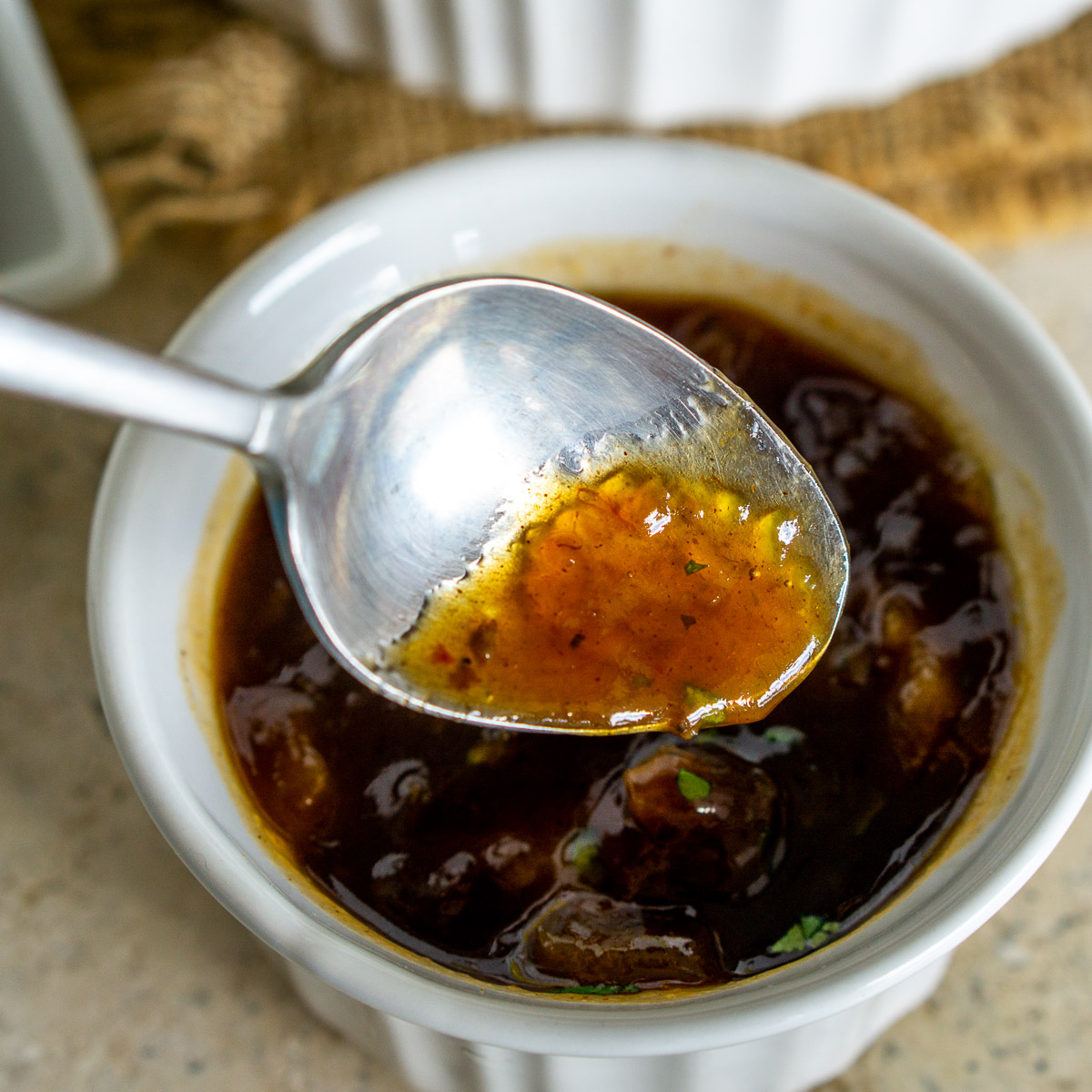 Spoon showing texture of peach preserves glaze with BBQ sauce