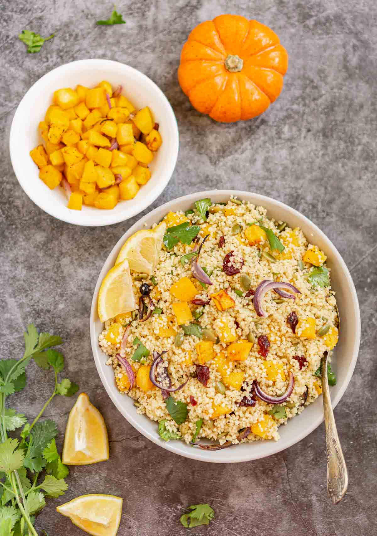Bowl of pumpkin couscous salad with a bowl of roasted cubed pumpkin next to it.