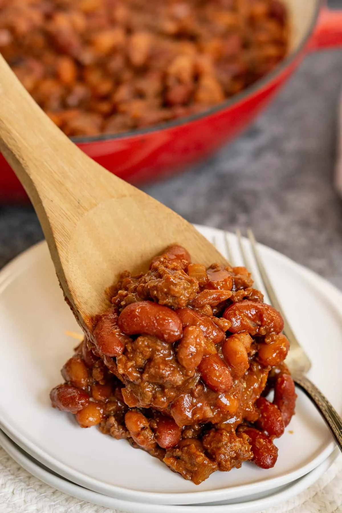 Adding baked beans with ground beef to a plate