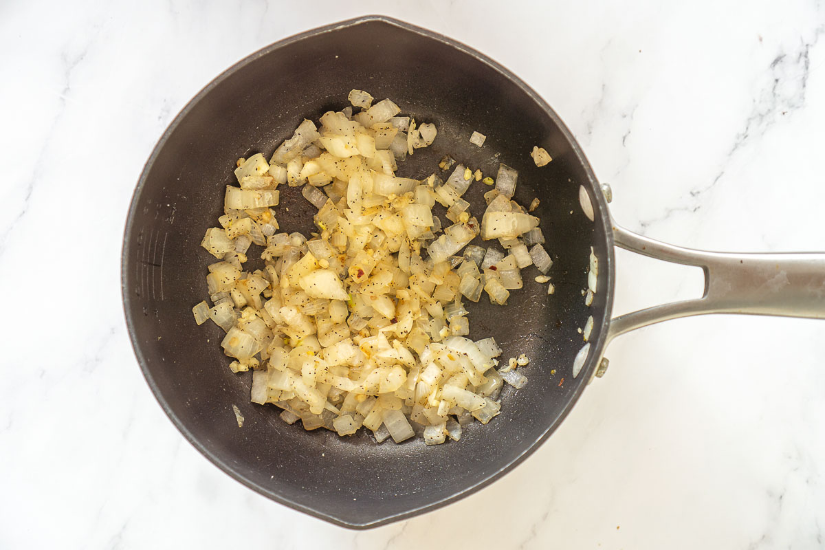 Diced onions and minced garlic sautéing in a soup pot
