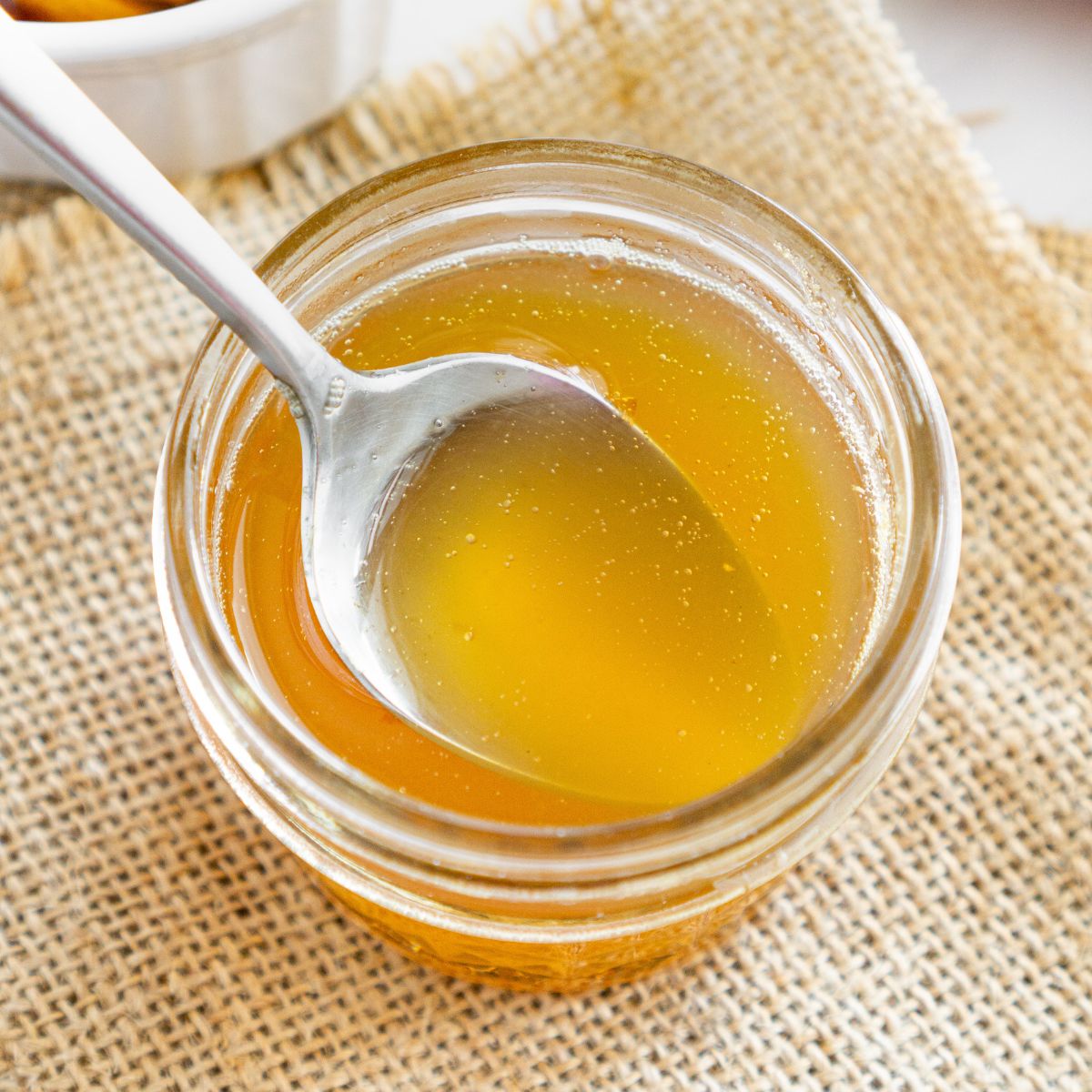 Spoon getting some honey ginger syrup from a jar
