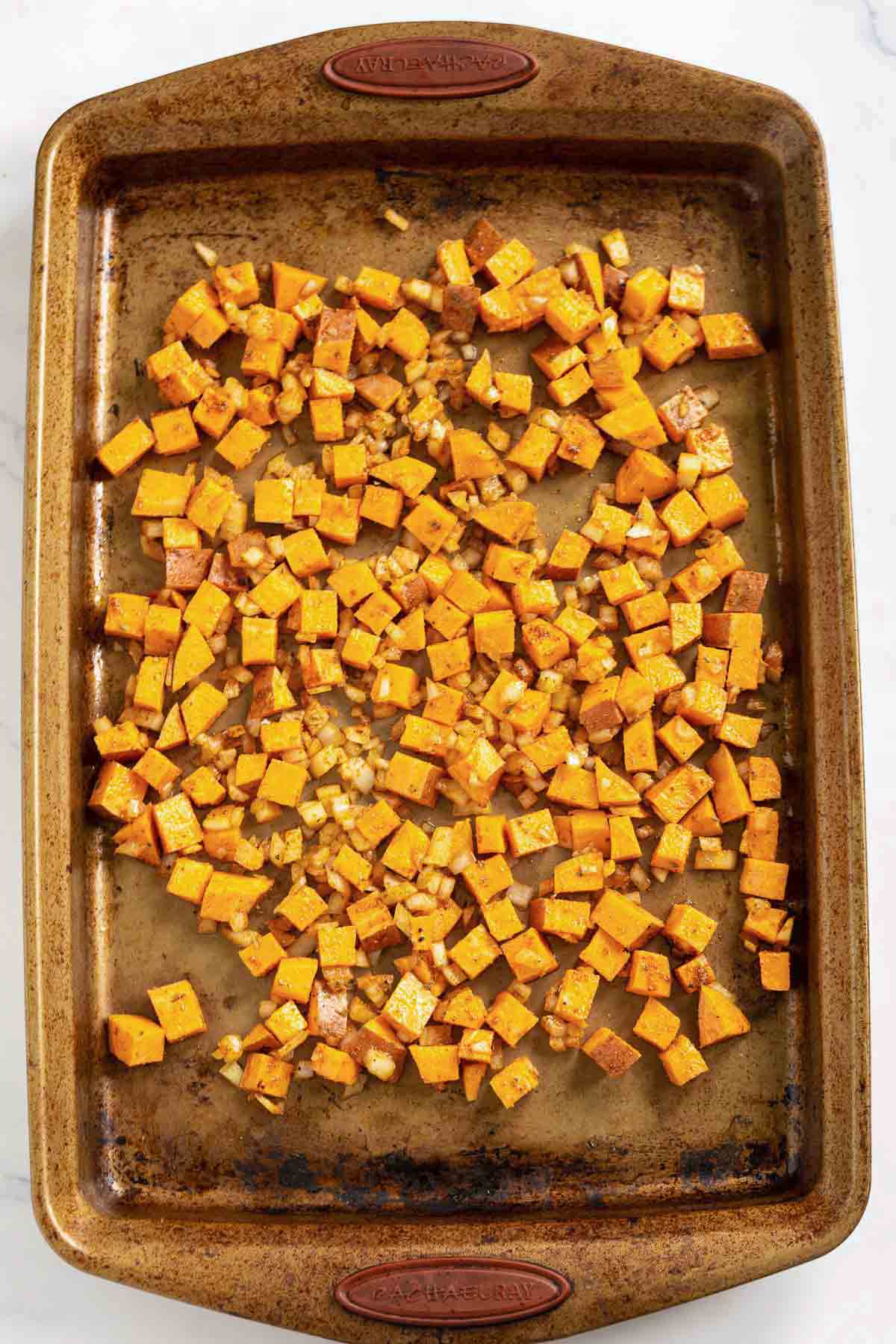 Seasoned cubed sweet potato on a baking tray