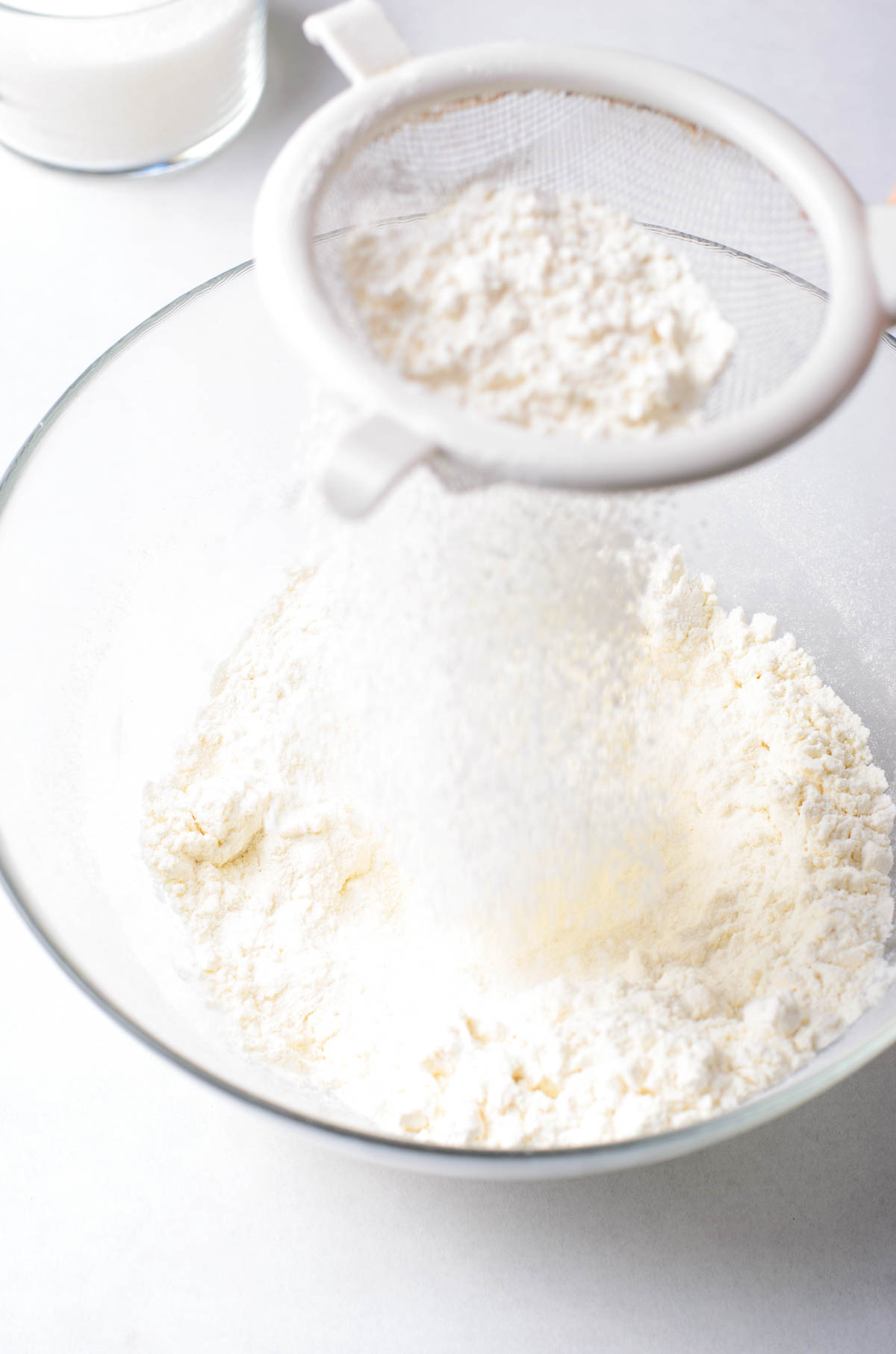 Sifting flour into a bowl with sugar