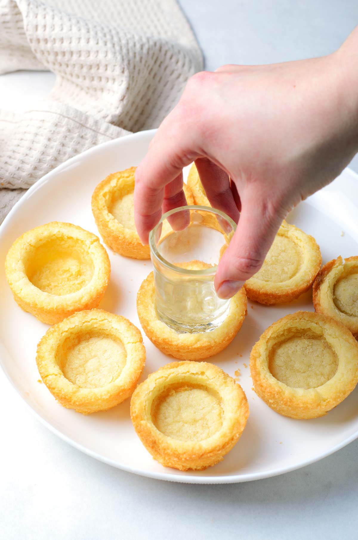 Using the bottom of a shot glass to press into baked sugar cookies to make a cup