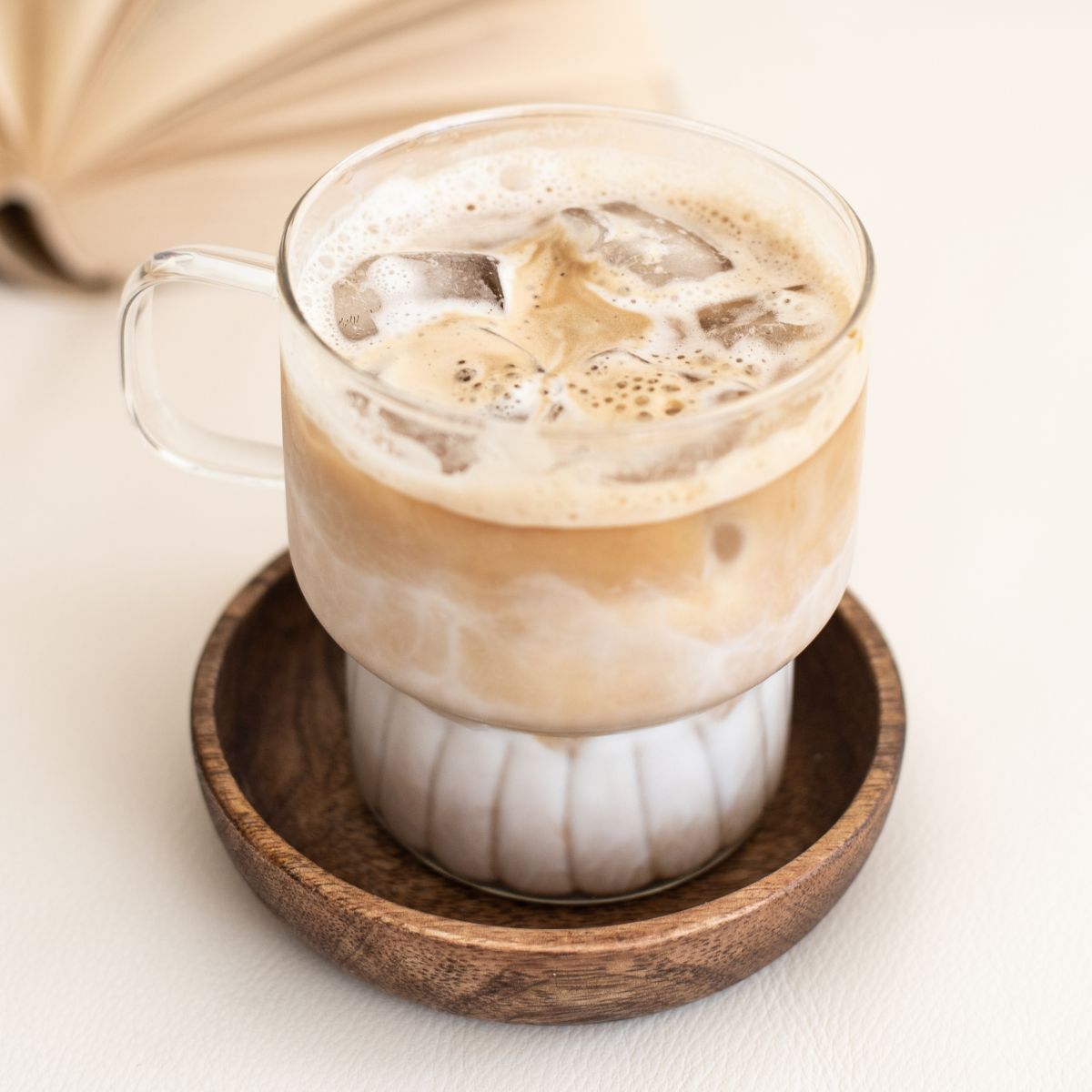 Iced lavender latte in a glass with a wooden coaster