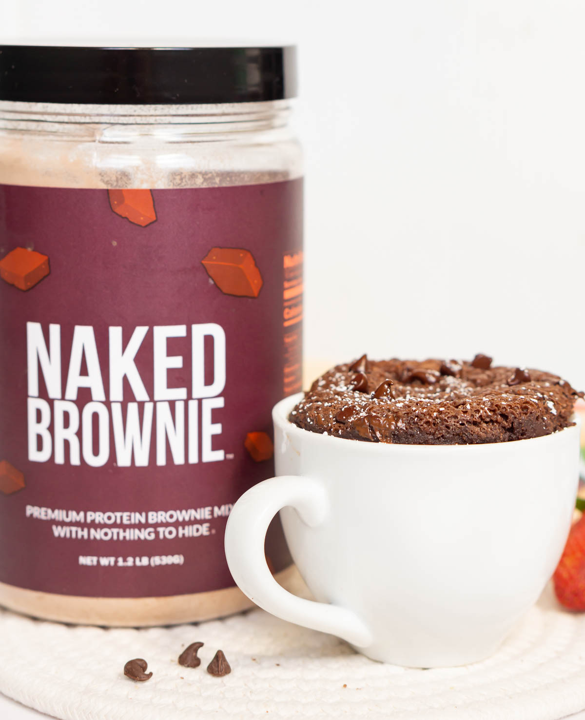 Mug with an individual microwave protein brownie with the Brownie Mix in the background