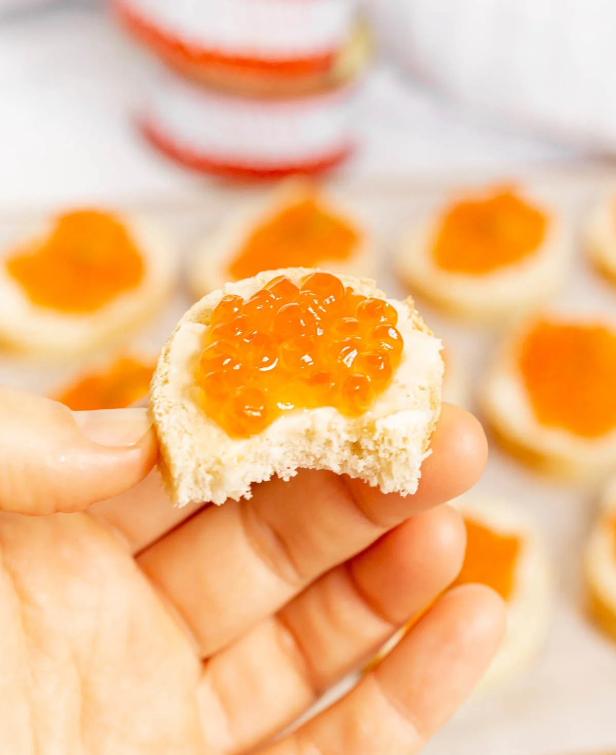 Hand holding a salmon roe toast with a bite taken out of it