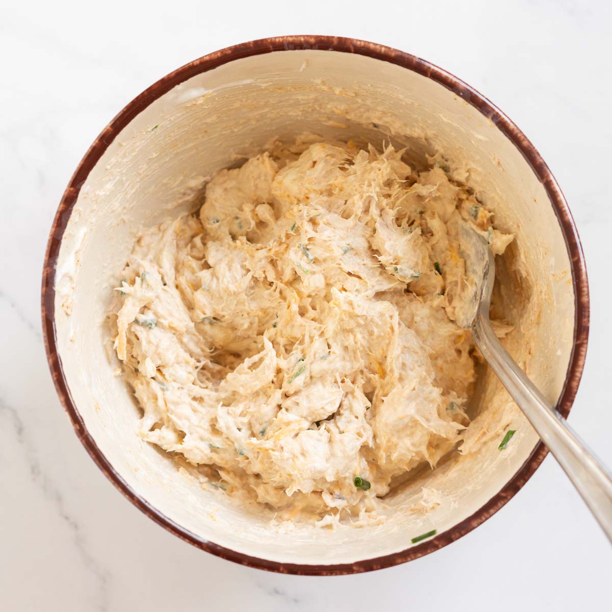 Bowl with cream cheese, shredded cheese, and tuna mixture.