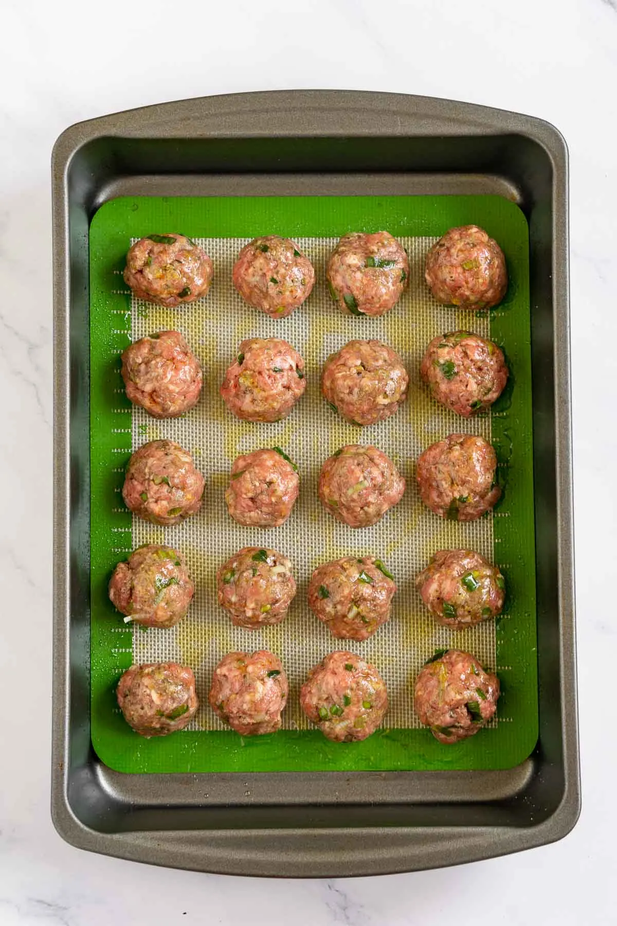Uncooked bison meatballs on a baking pan