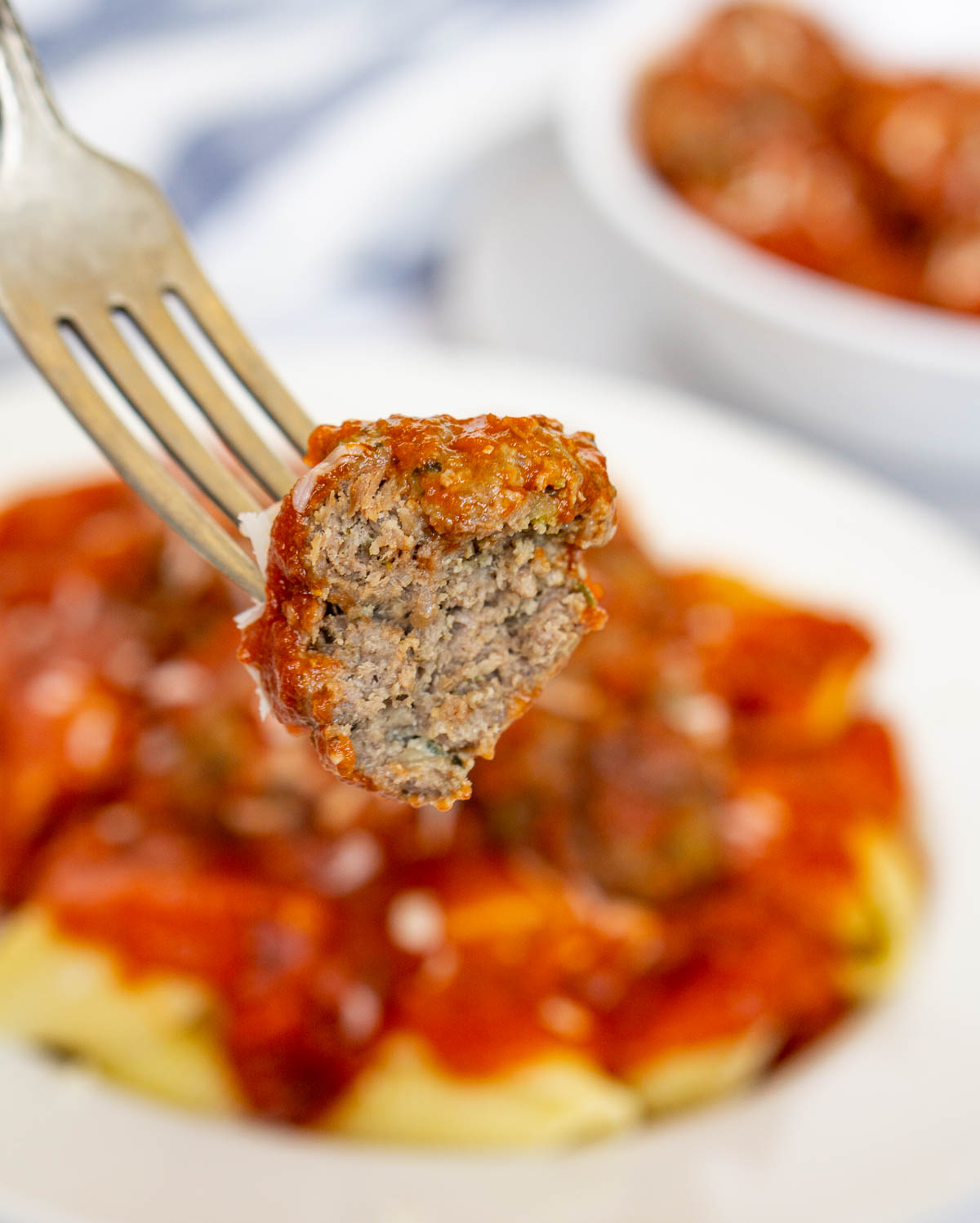 Fork holding bison meatball with a bite taken out of it to show texture inside