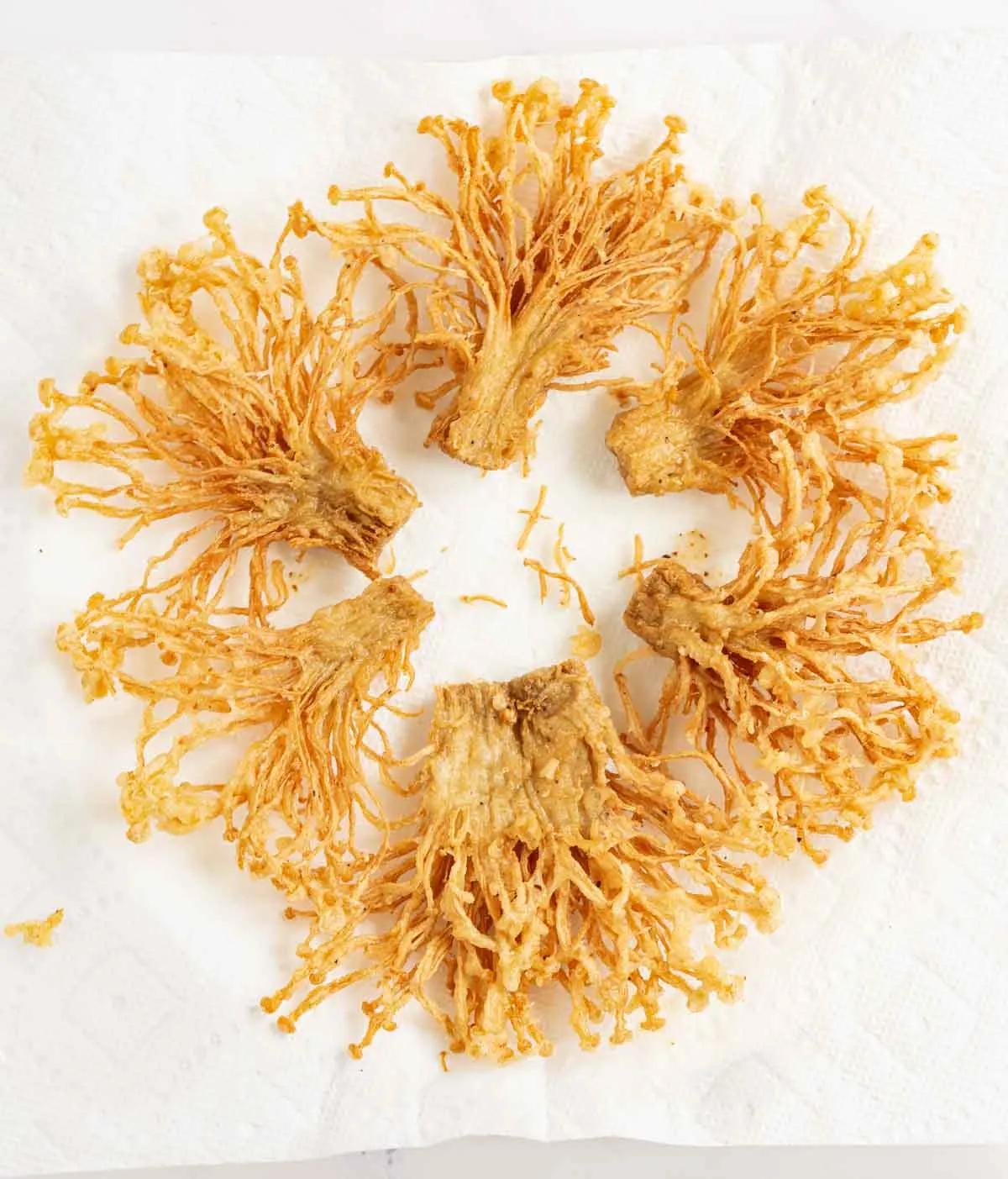 Fried enoki mushrooms draining on paper towel