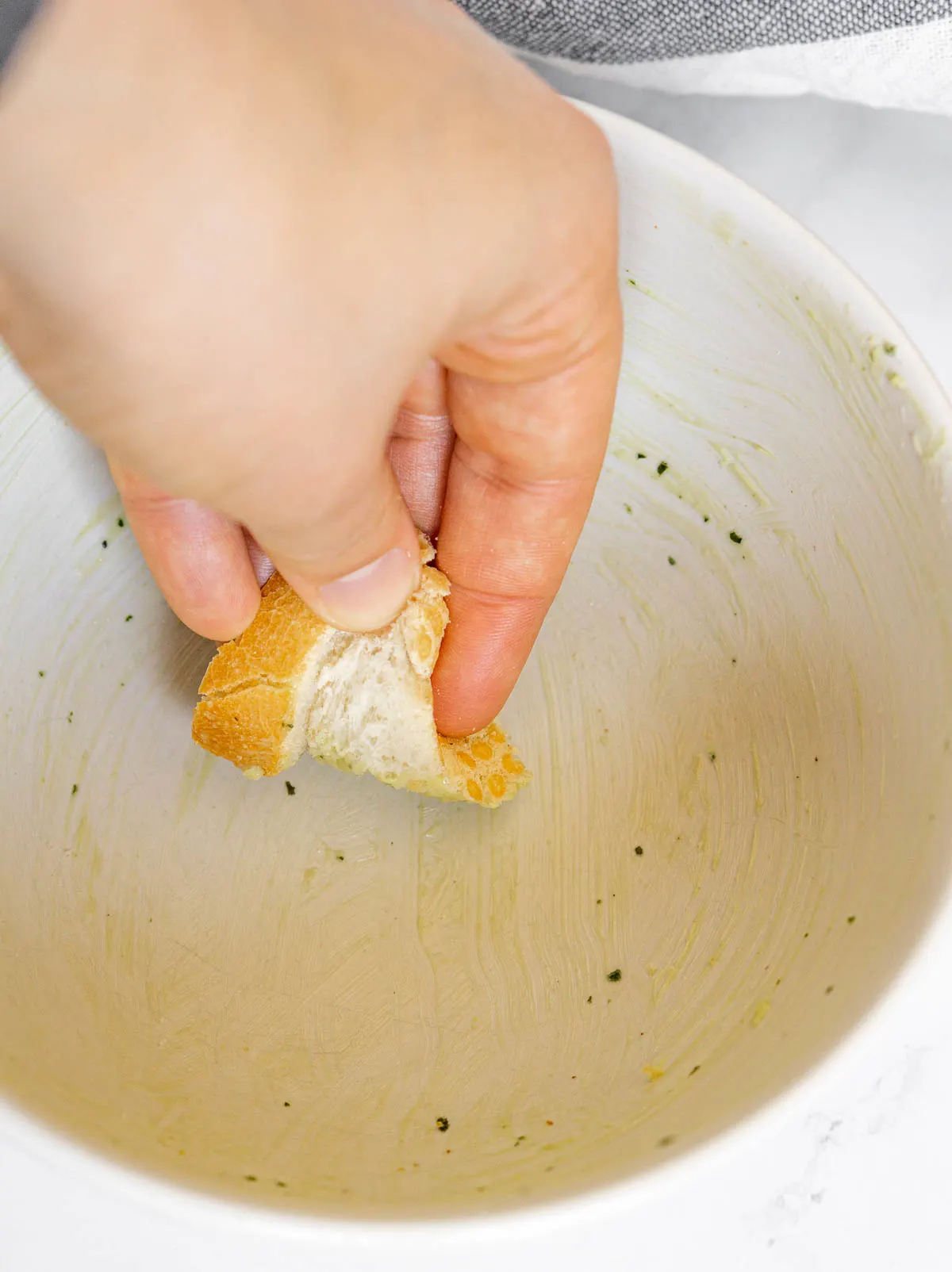 Using bread to wipe a bowl of pesto butter clean
