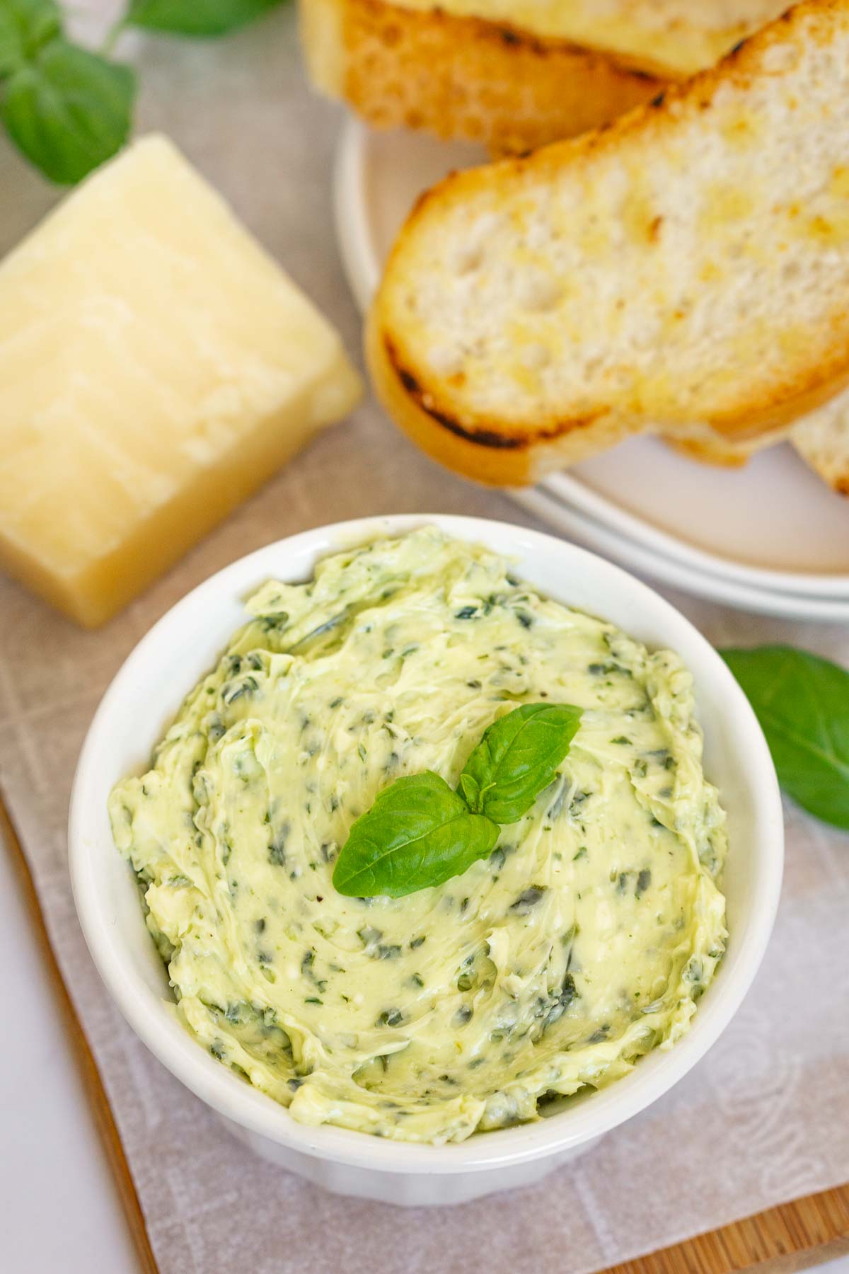 Serving board with a container of pesto butter and sliced toasts