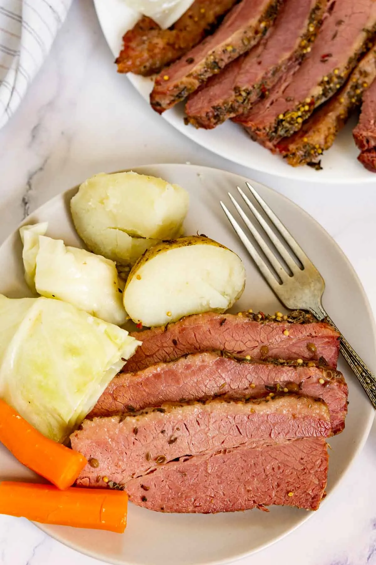 Corned beef dinner on a plate with potatoes, cabbage, and carrots.