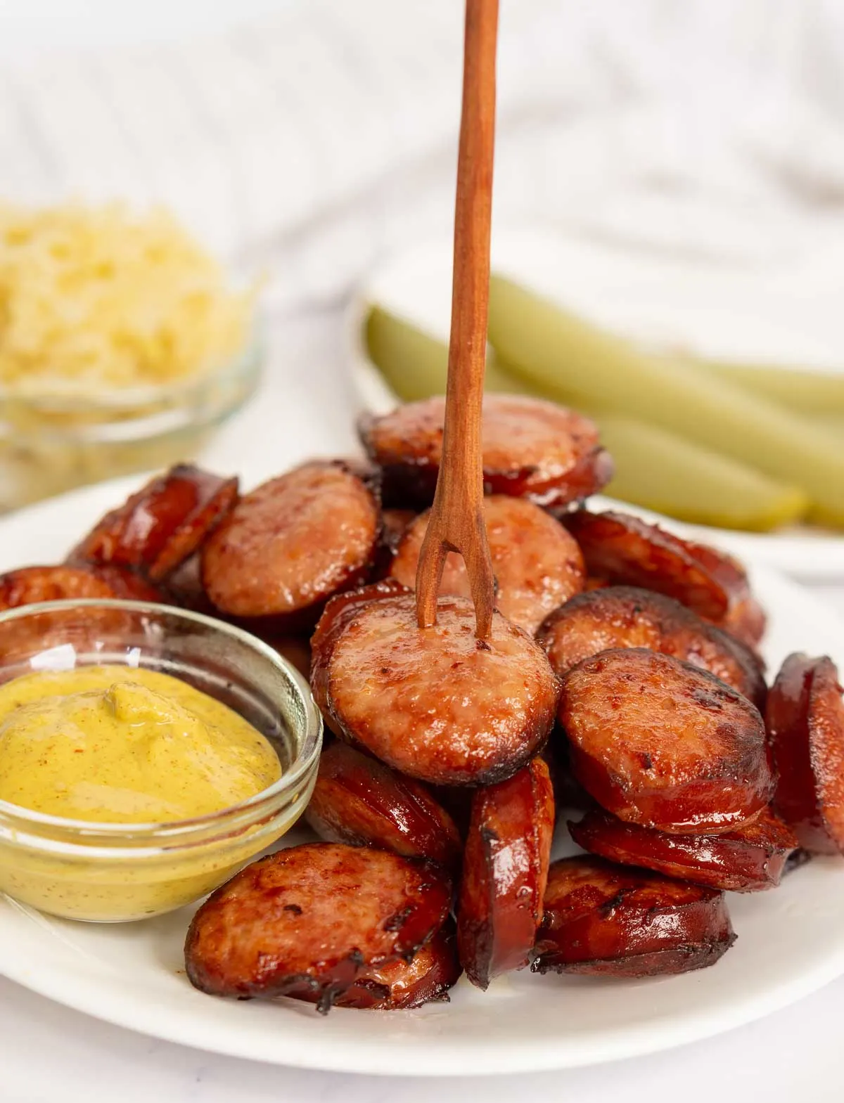 Kielbasa slices with a serving pick and mustard for dipping