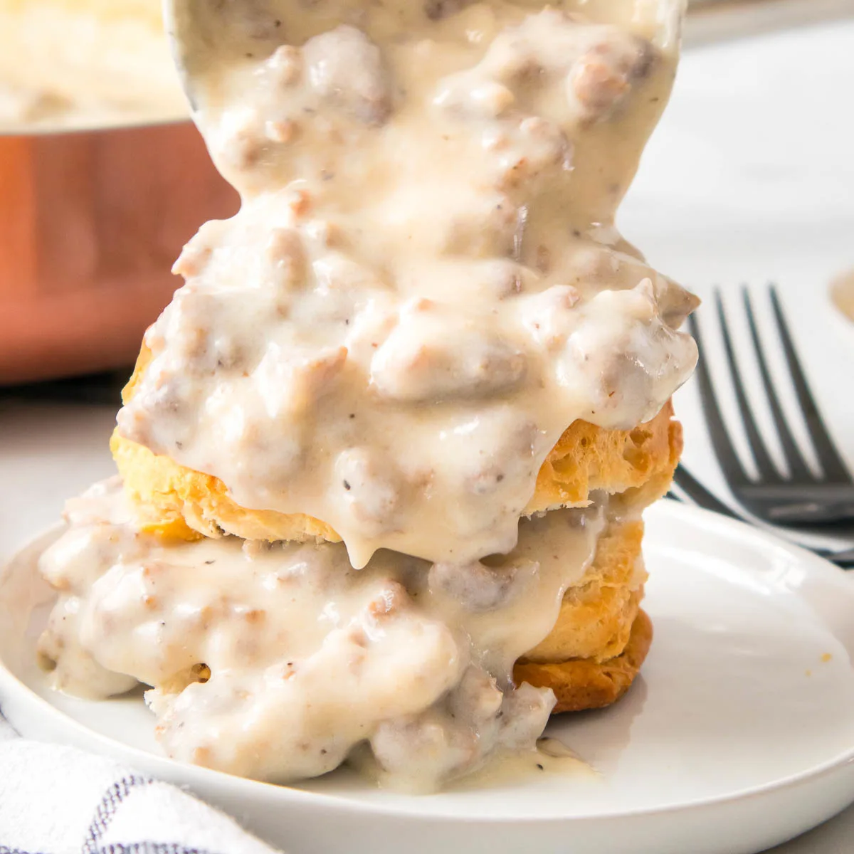 Ladling sausage gravy over a biscuit