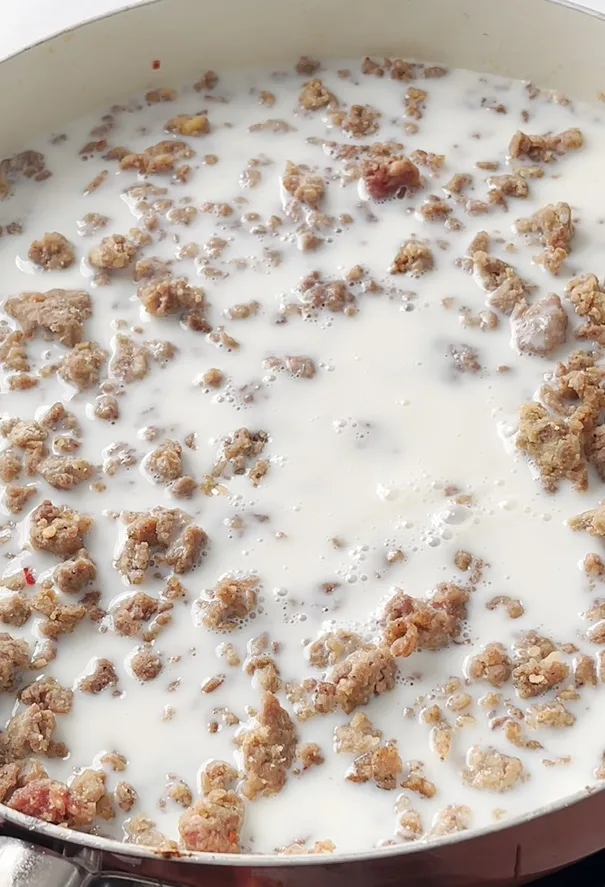 Milk added to a pan with sausage crumbles