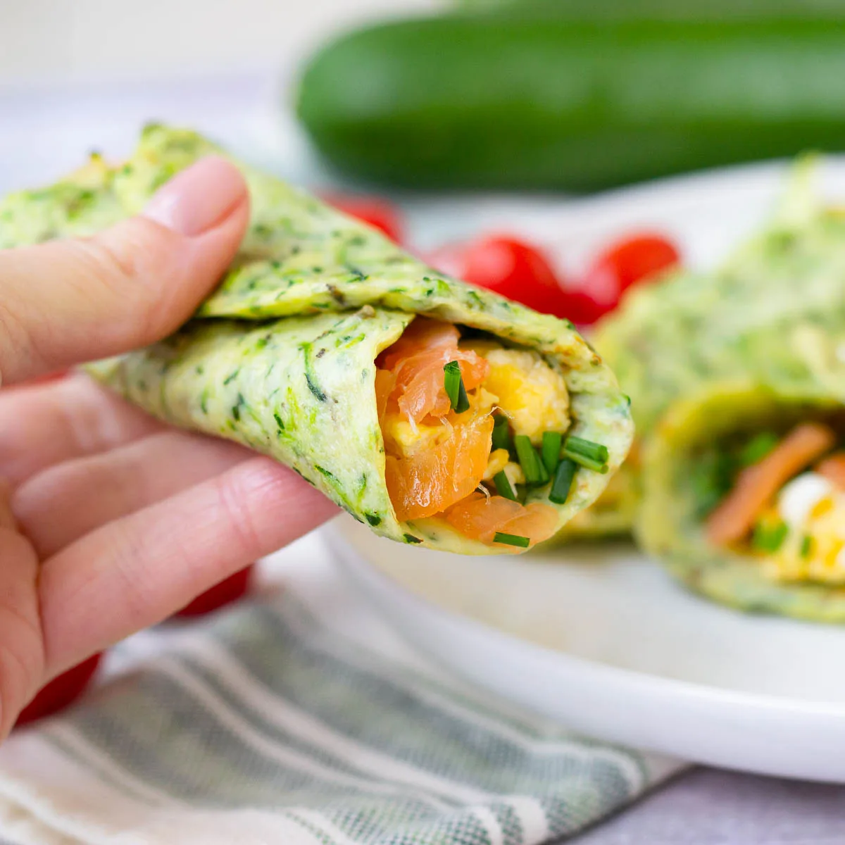 Hand holding zucchini breakfast wrap to show inside fillings