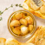 Garlic confit in oil surrounded by crostini with spread roasted garlic