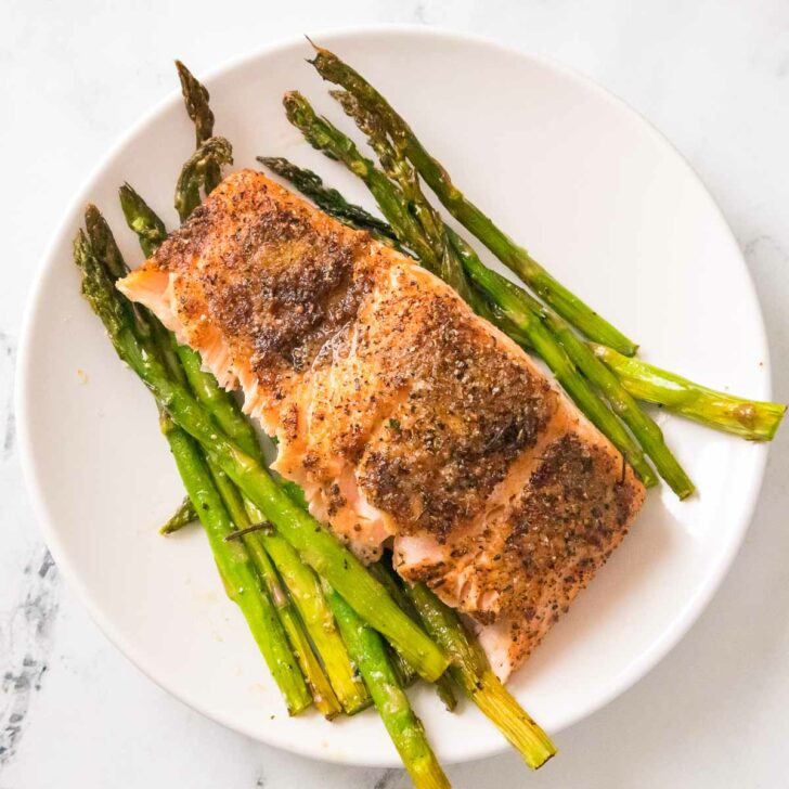 Plate of air fried salmon over asparagus