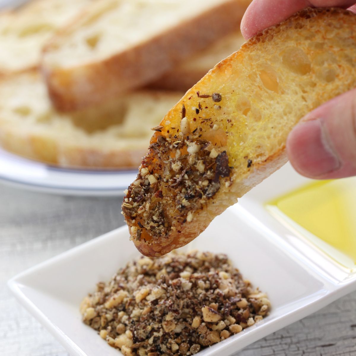Hand dipping bread into olive oil and dukkah